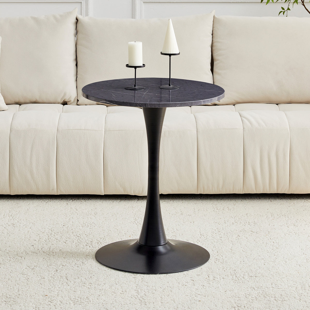 Black faux marble bistro table with a pillar candle and cone candle beside cushions, three-quarter view
