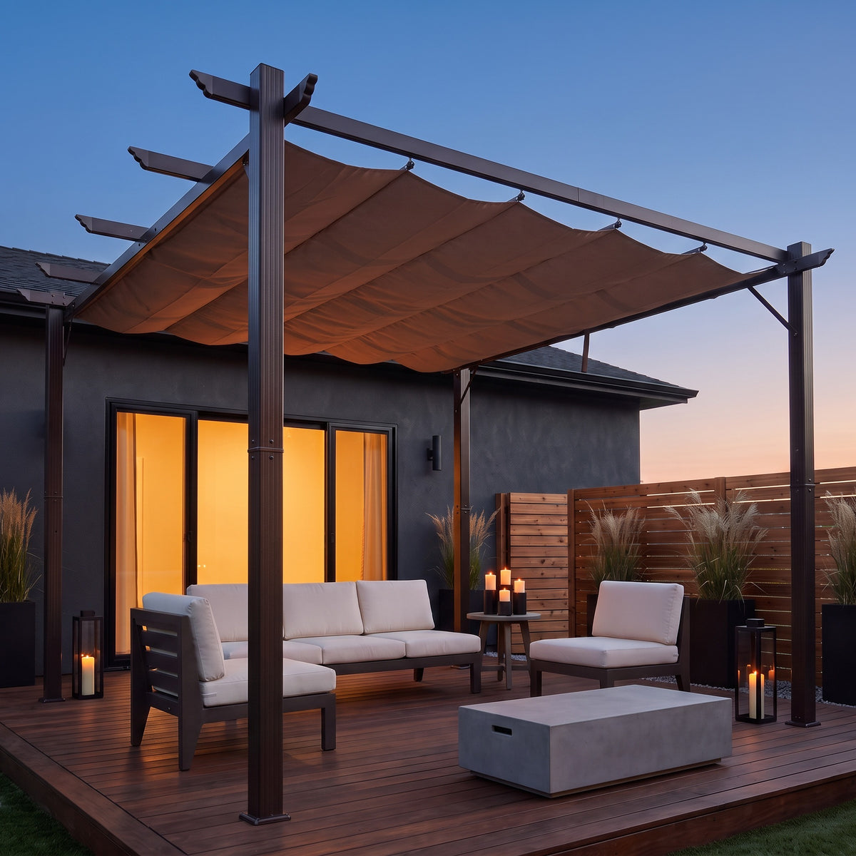 Brown aluminum 10x10 pergola with taupe retractable canopy over cream outdoor seating on a wood deck at dusk