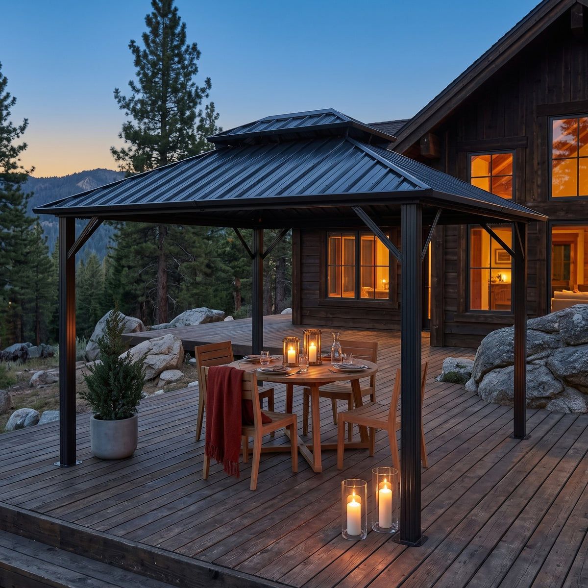 Gray double roof hardtop gazebo over a round wood dining table on a mountain cabin deck at dusk with candles
