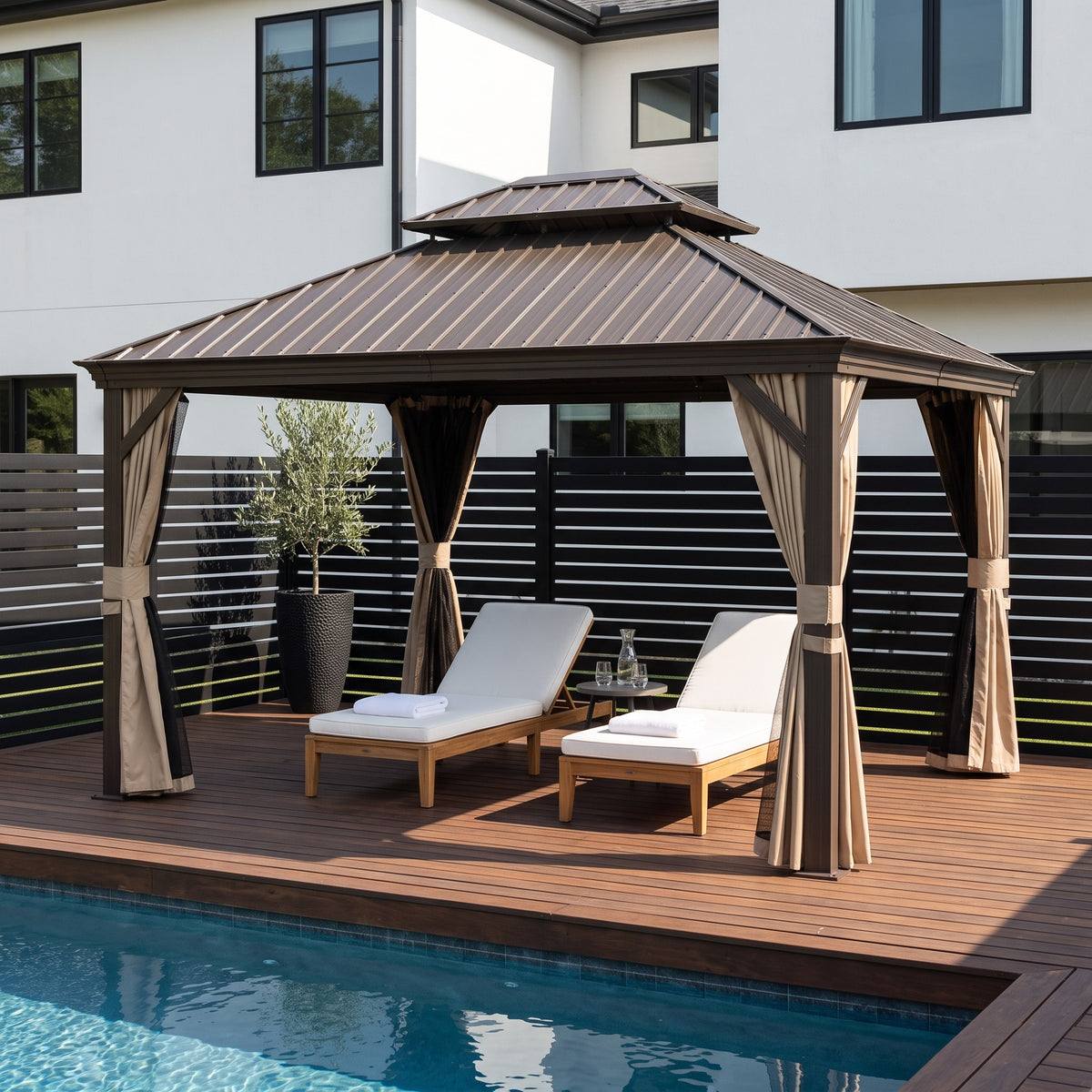 Brown aluminum 10x12 hardtop gazebo with tan curtains over two white lounge chairs on a pool deck