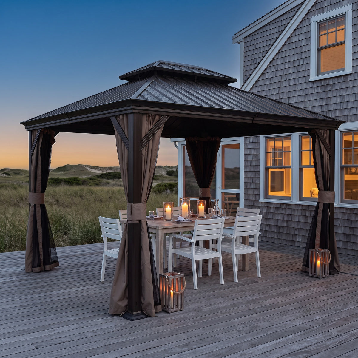 Dark brown hardtop gazebo with tied back curtains over a candlelit dining table on a beach house deck at dusk