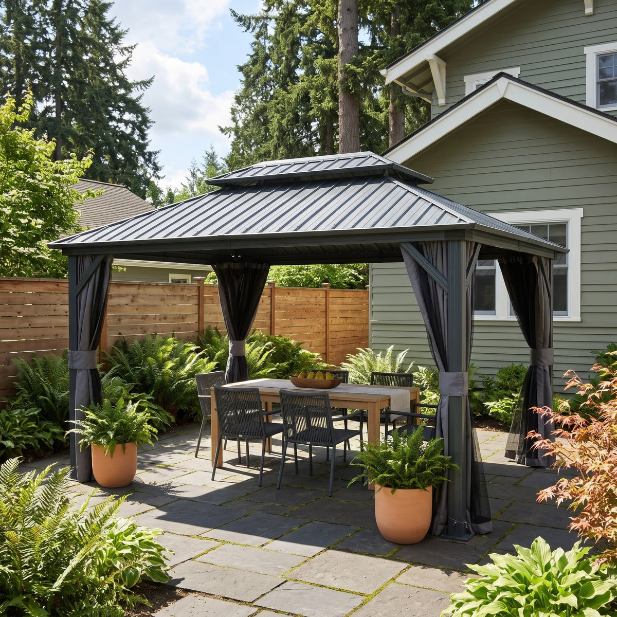 Gray double roof hardtop gazebo with tied back curtains over a wood dining table on a stone patio in daylight