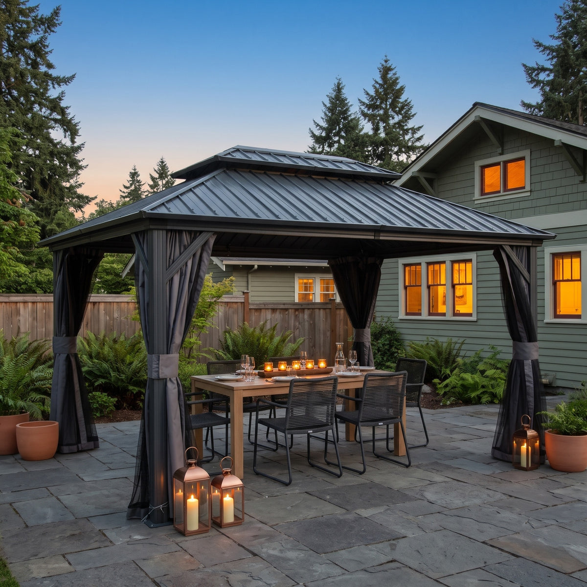 Gray aluminum 10x12 double roof hardtop gazebo with tied back curtains over a dining table on a stone patio at dusk