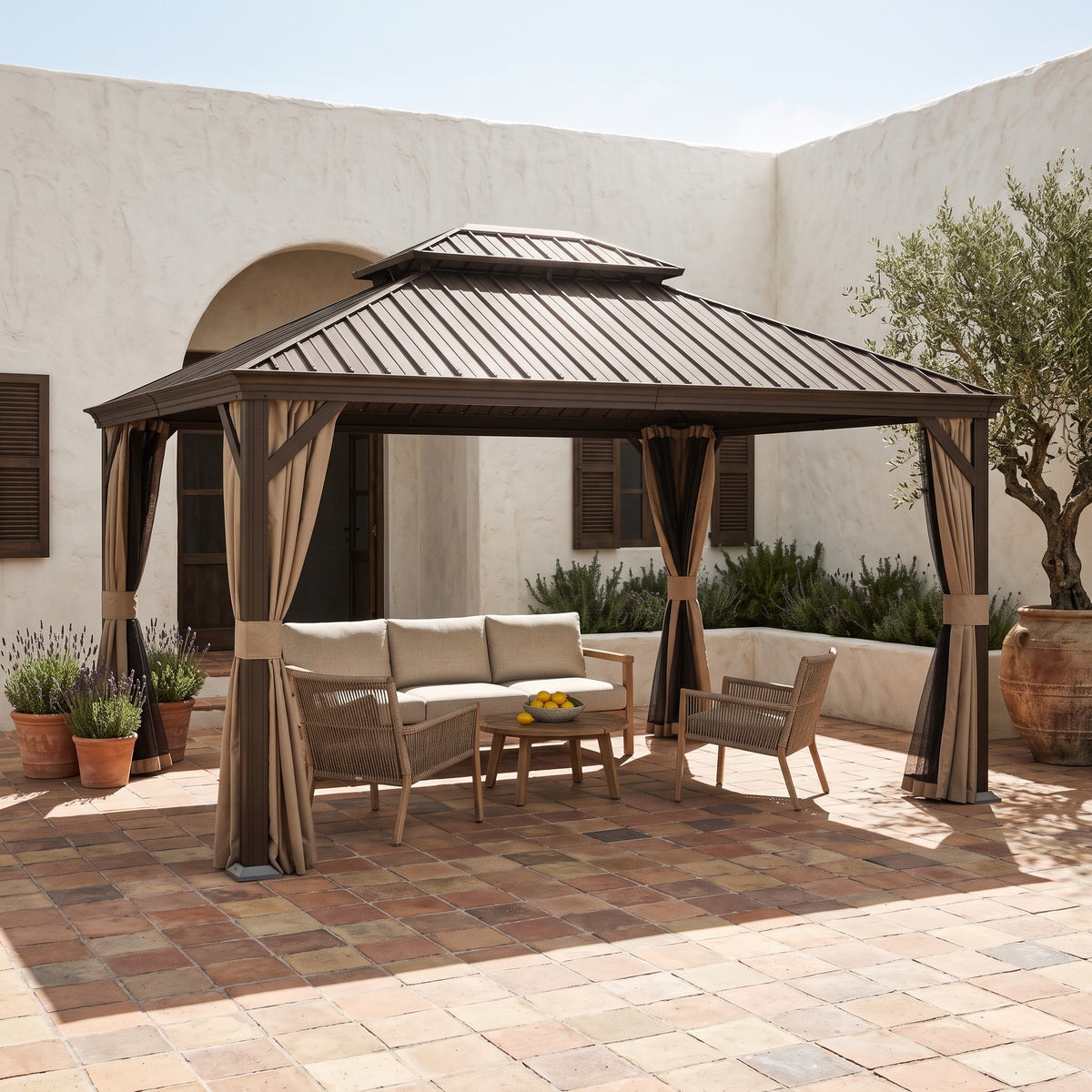 Brown metal double roof hardtop gazebo with tan curtains over a wood lounge set in a sunny tiled courtyard