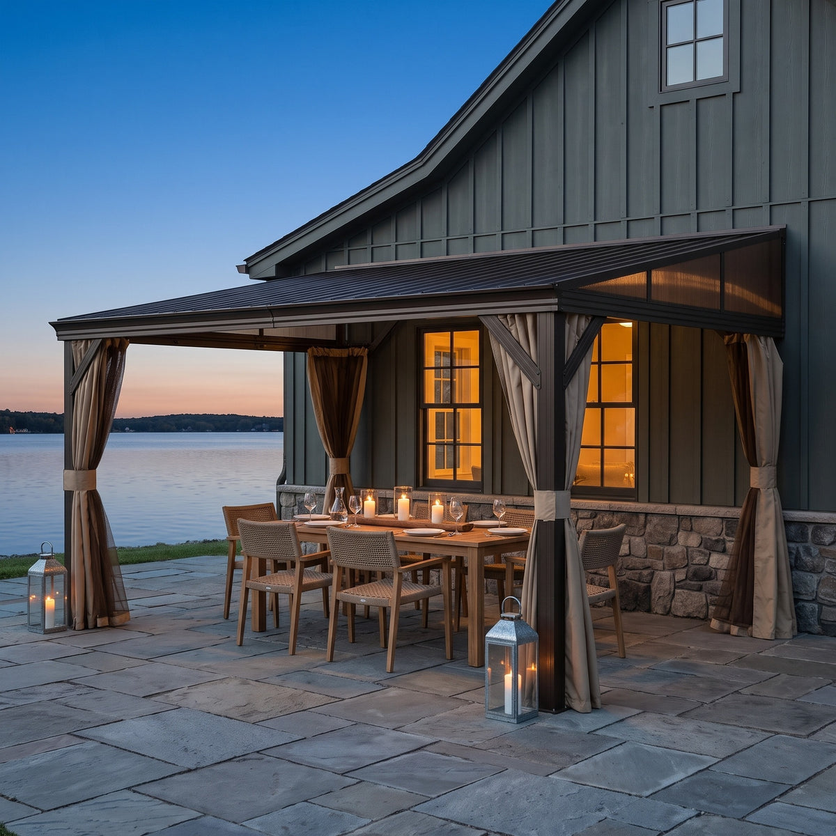 Dark brown steel lean-to hardtop gazebo with tied beige curtains over a candlelit dining table by a lake at dusk