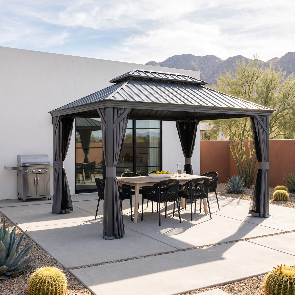 Dark gray 10x14 hardtop gazebo with tied back curtains over a dining table on a desert concrete patio