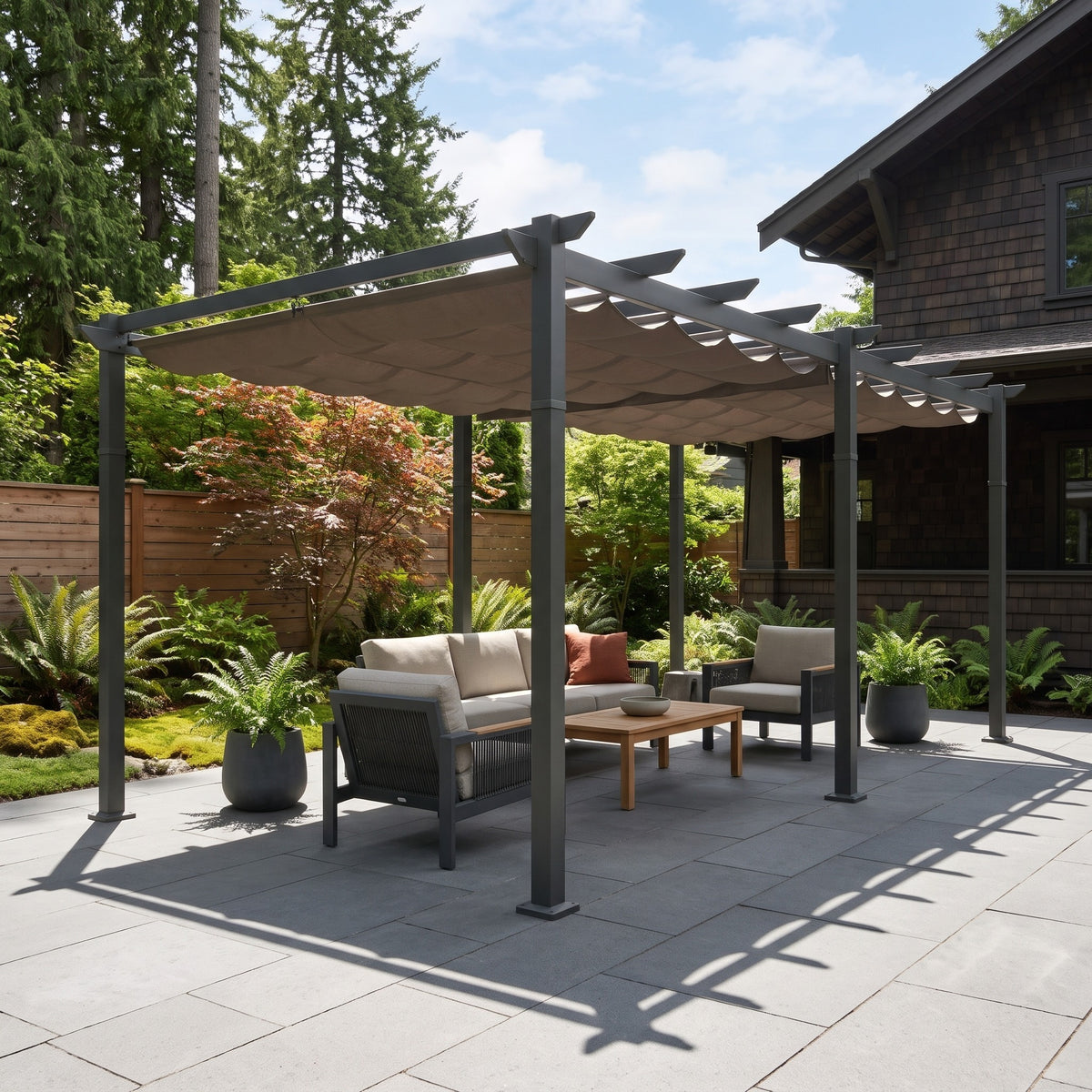 Dark gray aluminum 11x20 pergola with taupe retractable canopy over a patio sofa set on stone pavers in sun