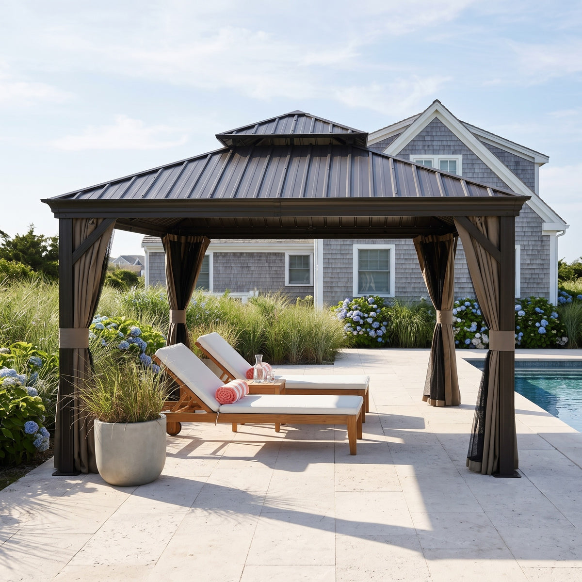 Brown aluminum 12x12 double roof hardtop gazebo with tied back curtains over two loungers by a pool