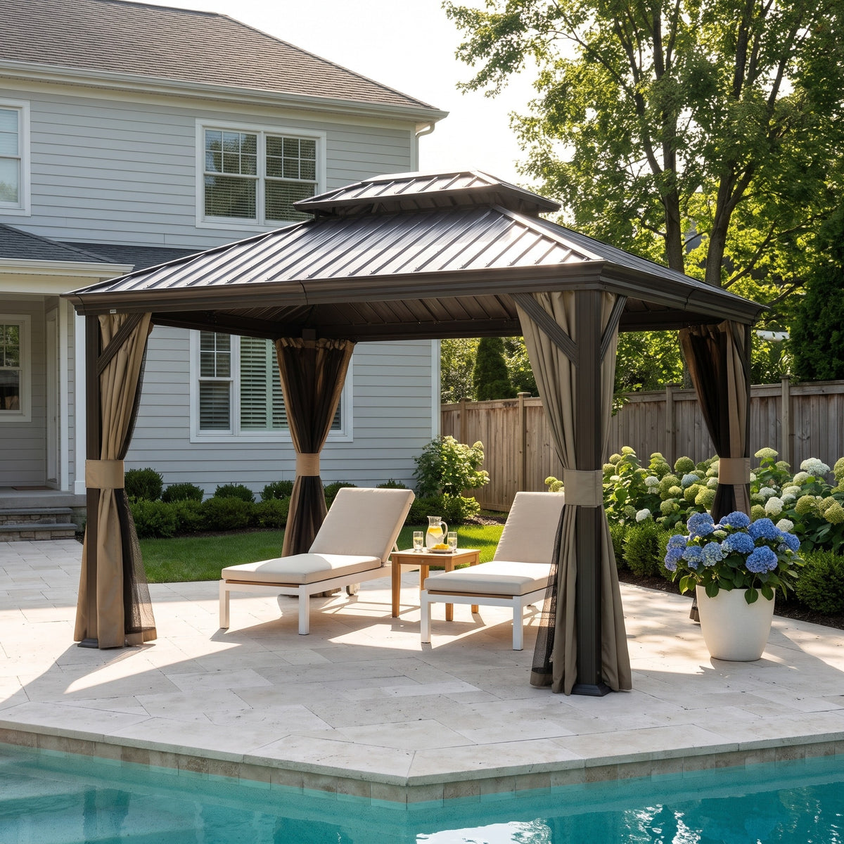 Brown 12x14 hardtop gazebo with tied back curtains over two lounge chairs beside a pool
