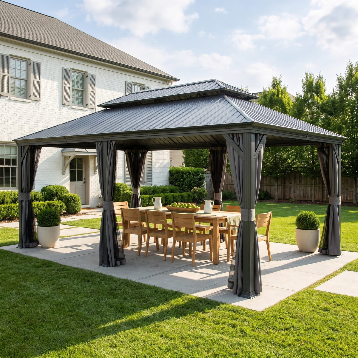 Dark gray 14x20 hardtop gazebo with tied gray curtains over a teak dining table on a backyard patio in afternoon sun