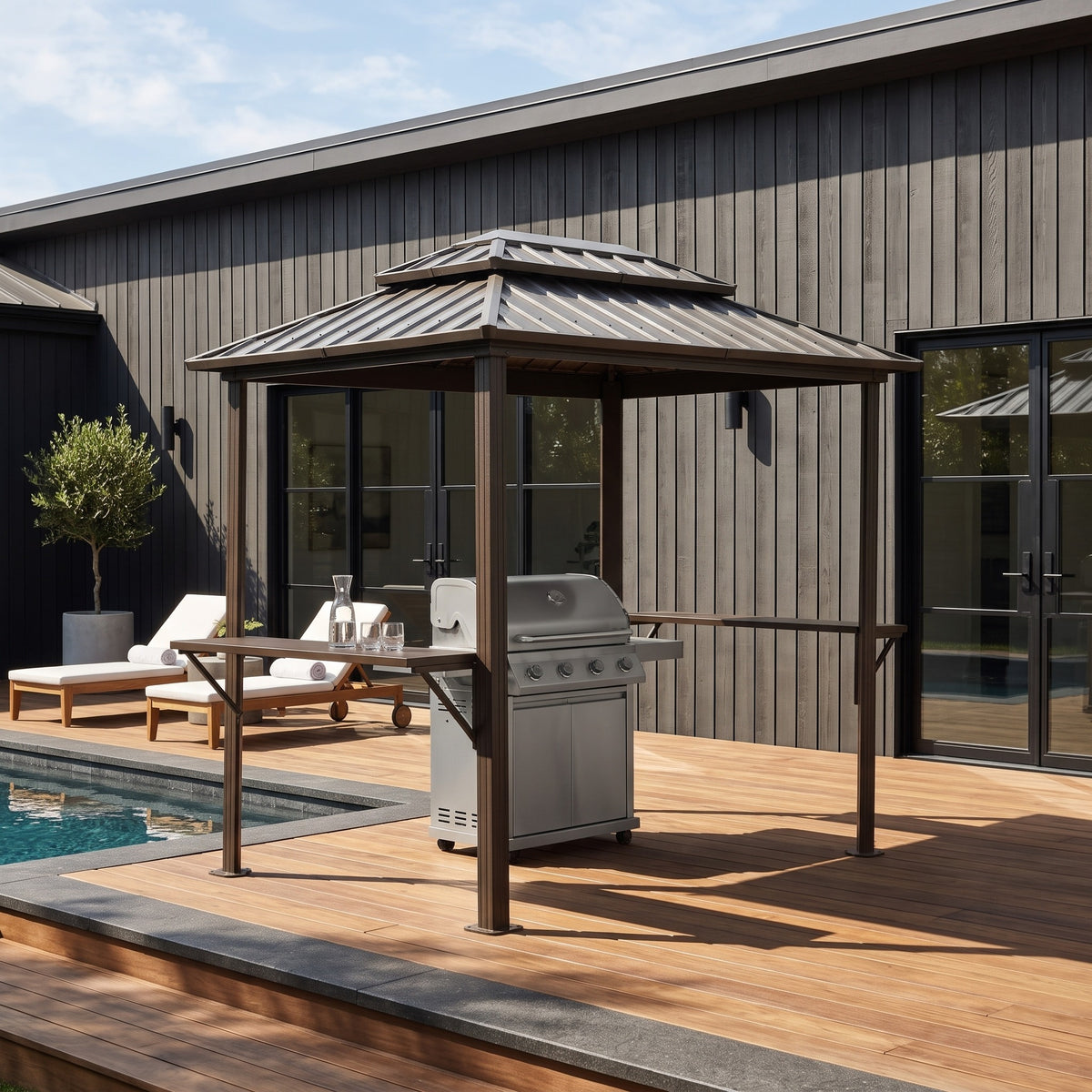 Brown metal 6x8 double roof grill gazebo with side shelves over a gas grill on a poolside wood deck