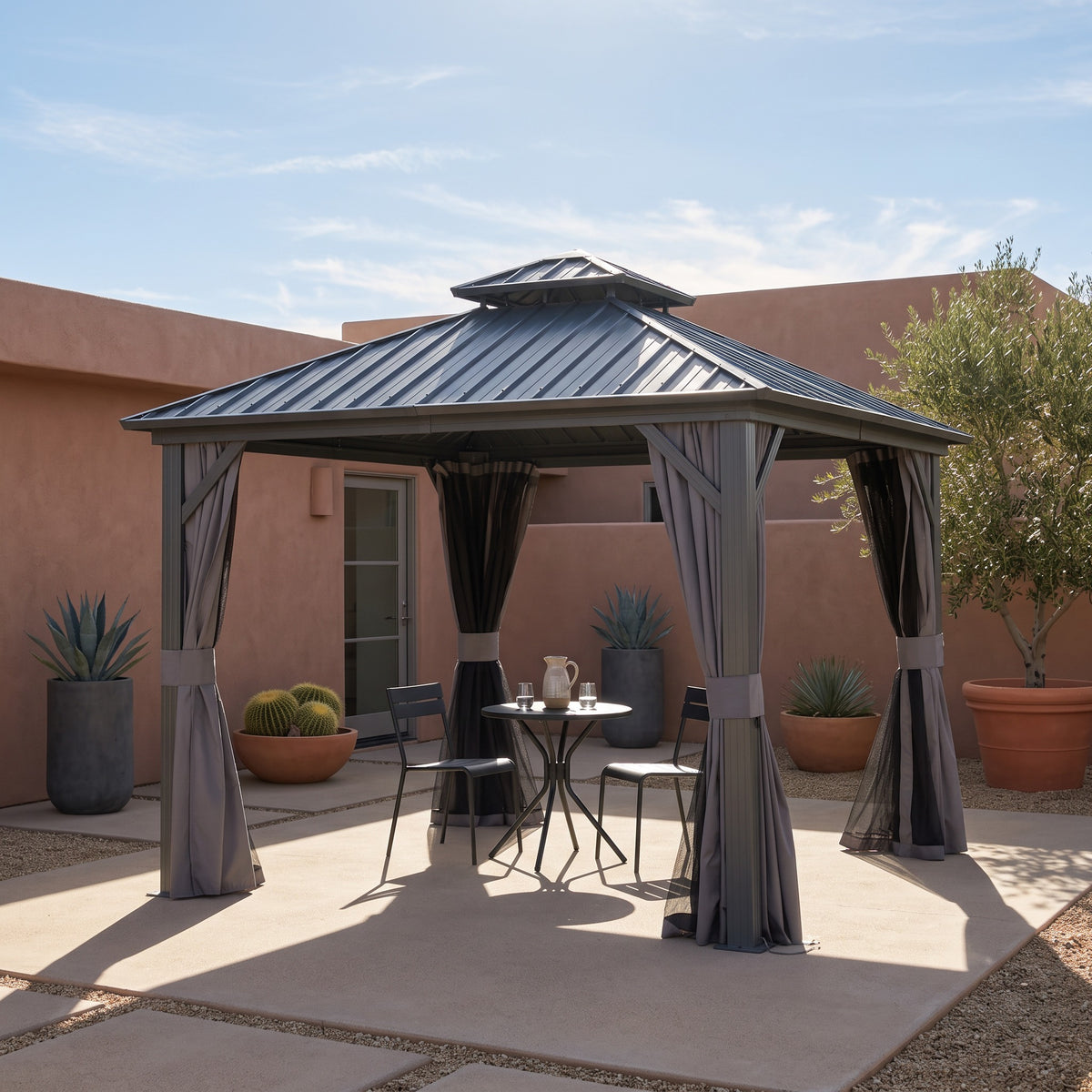 Gray aluminum 8x8 double roof hardtop gazebo with tied back curtains over a bistro table in a desert courtyard