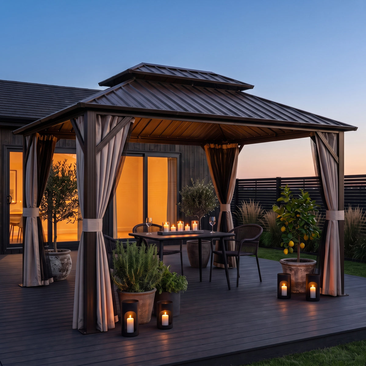 Brown aluminum hardtop gazebo with tied back curtains over a candlelit table on a dark deck at dusk