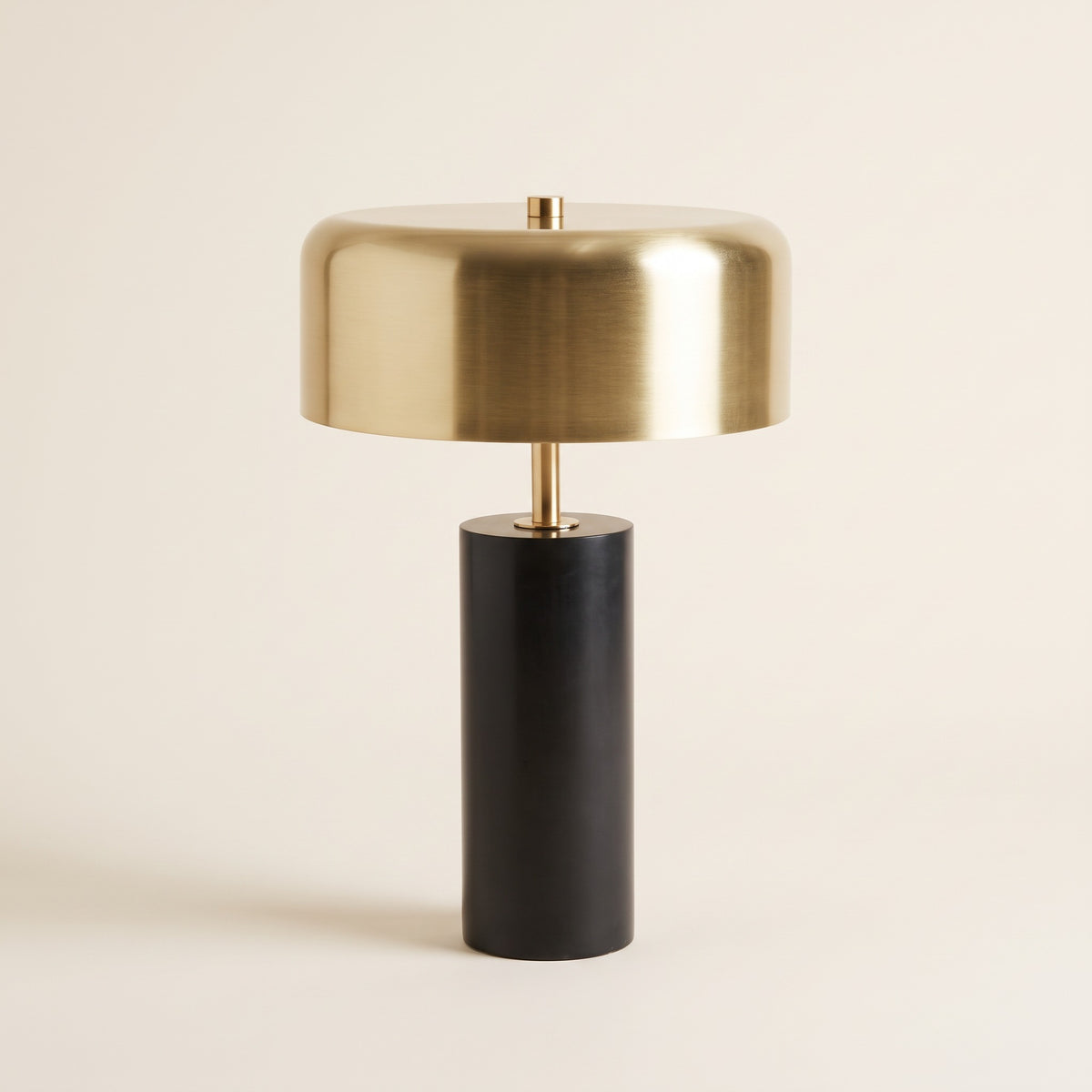 Black marble table lamp with gold metal drum shade and brass stem on a warm ivory backdrop