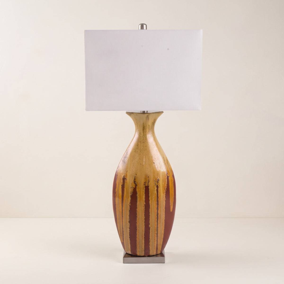 Multicolor drip glaze ceramic table lamp with white rectangular fabric shade on an ivory backdrop