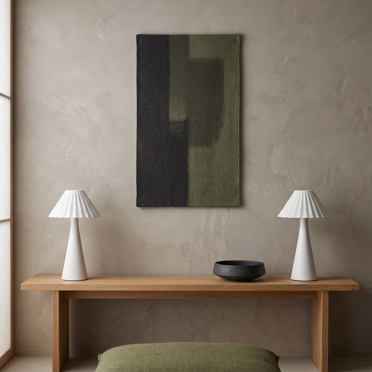 Two white pleated metal table lamps on an oak console below a charcoal and olive woven wall hanging