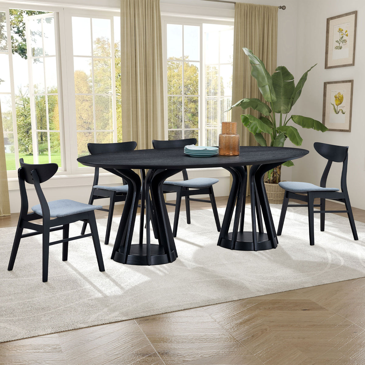 Black oval pedestal dining set with four chairs in a bright dining room