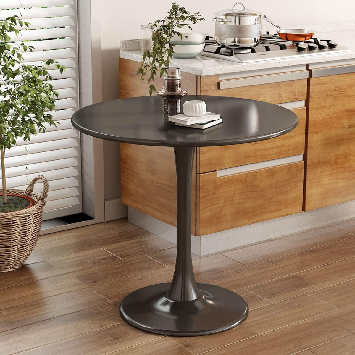 Black round dining table styled with books and decor in a kitchen nook, three-quarter view