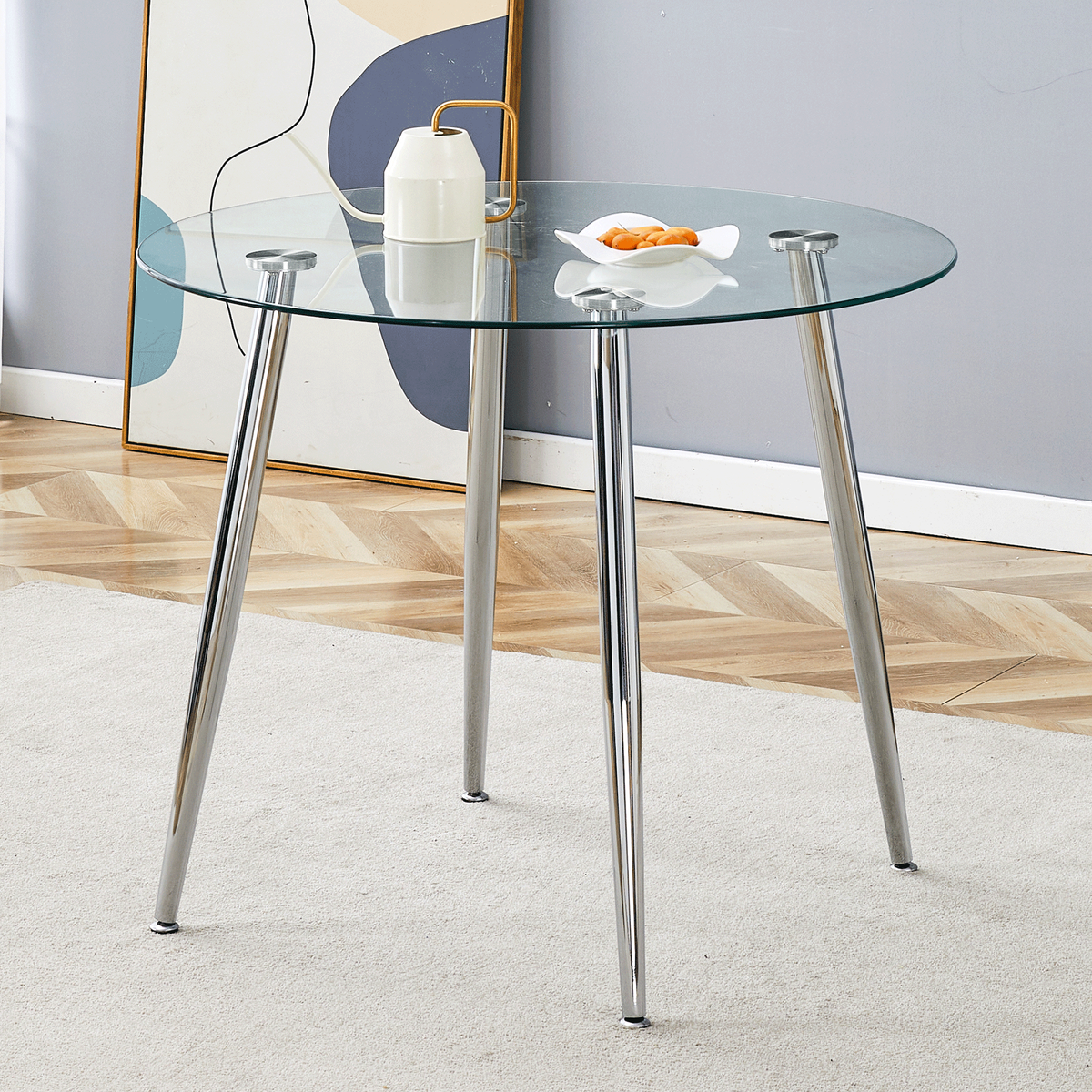 Front view of the round glass dining table styled with a watering can and fruit dish in a bright room