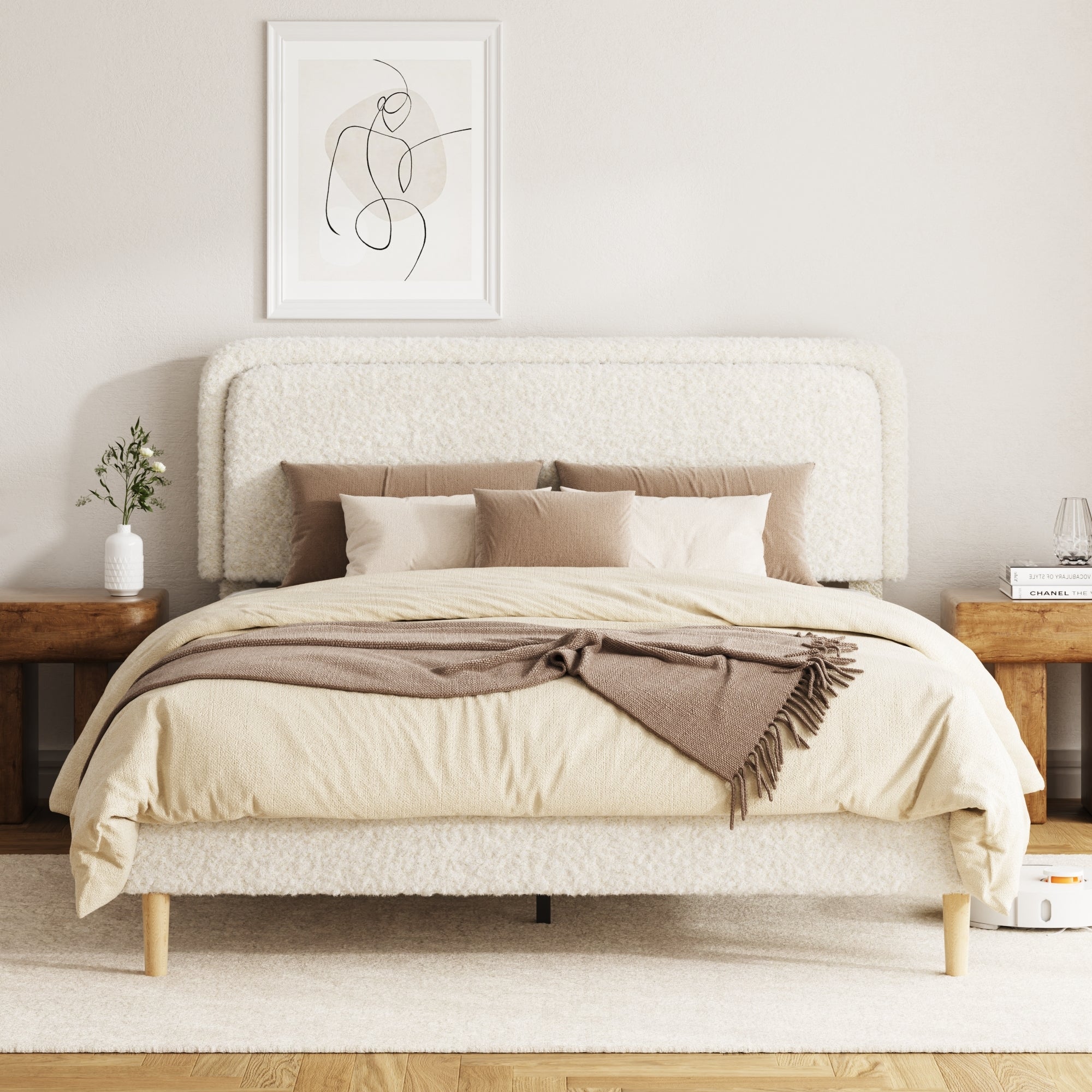 Beige plush upholstered queen bed with a rounded boucle headboard and wood legs, styled bedroom with nightstands and art