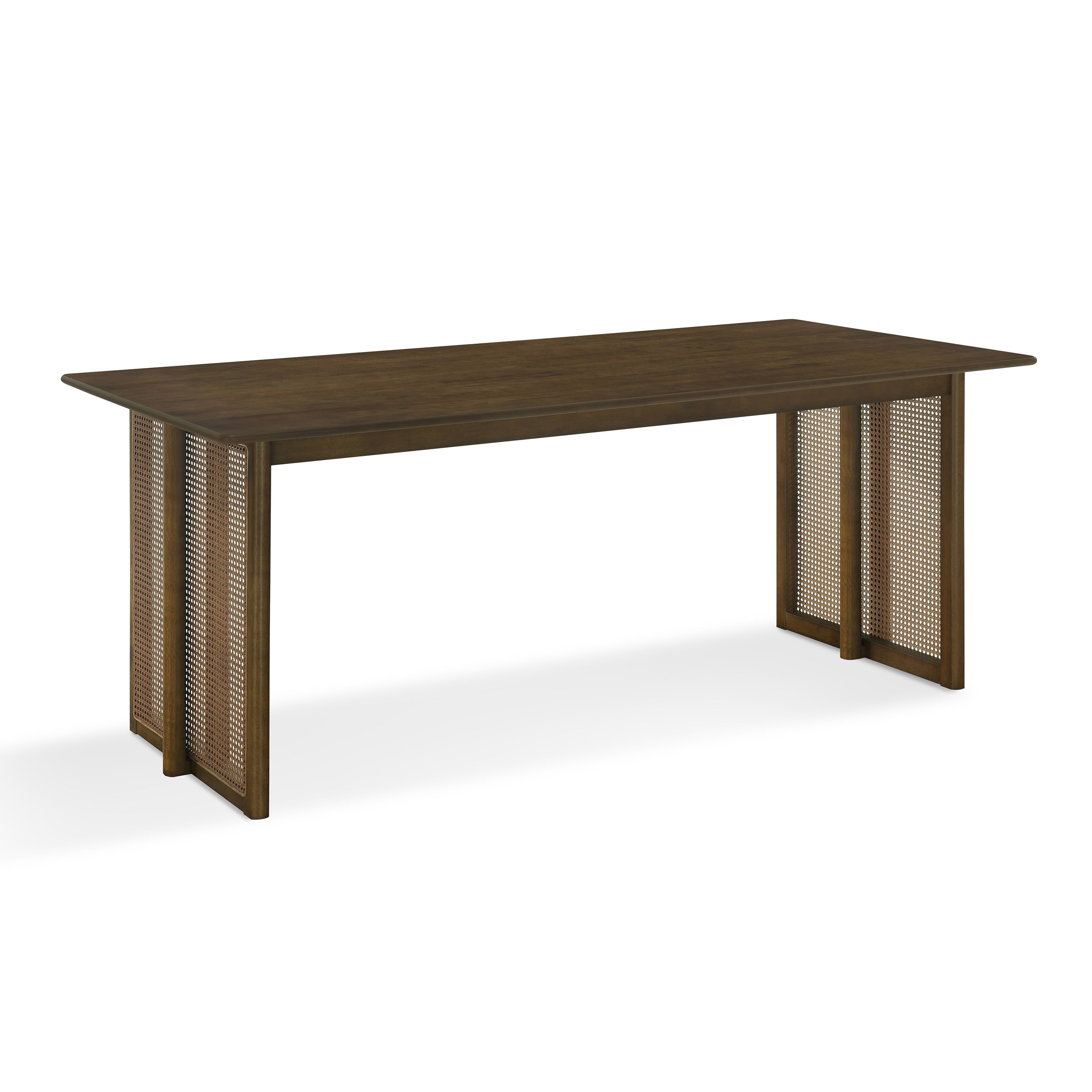 Three-quarter studio view of the walnut solid wood dining table with woven cane panel legs, white background
