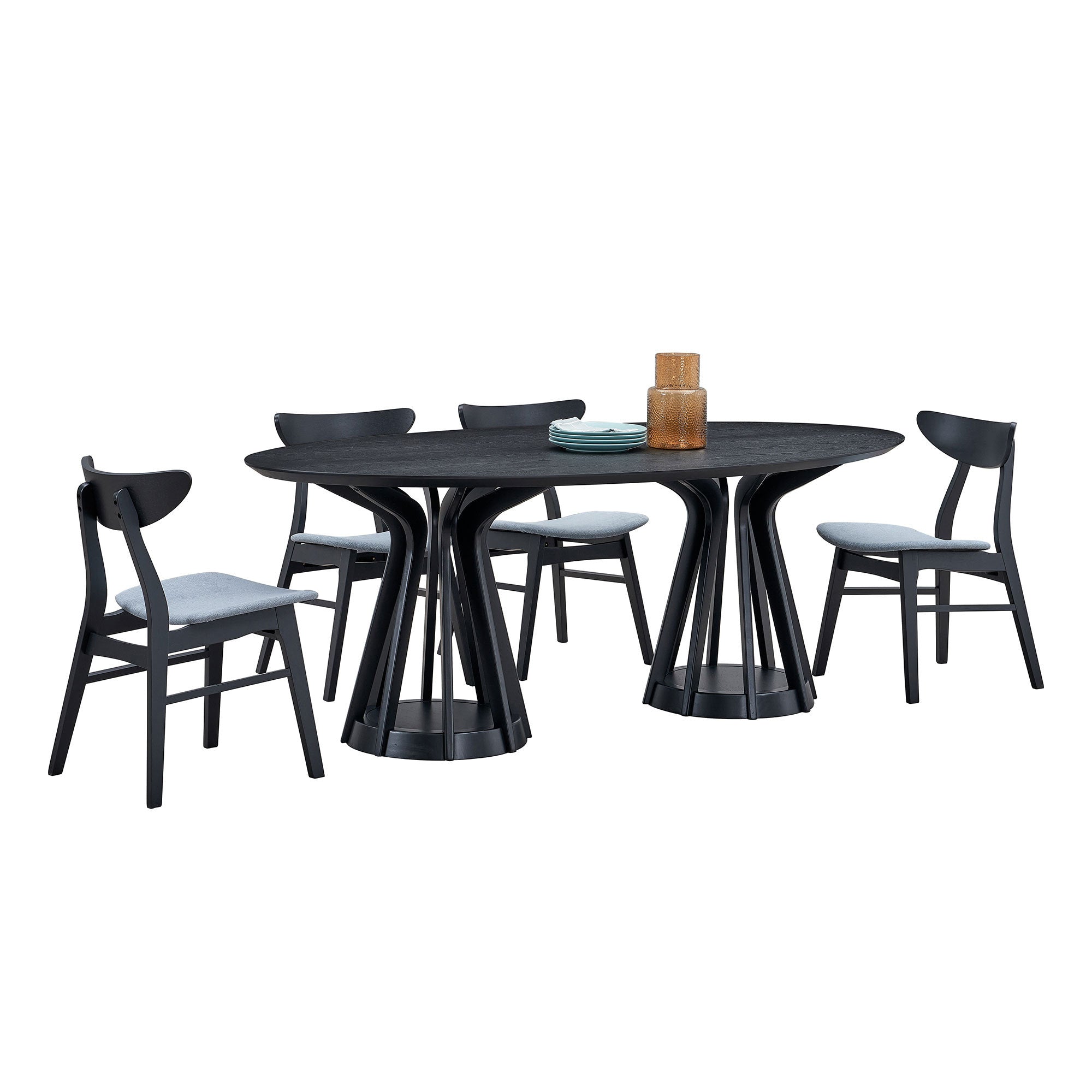 Black oval pedestal dining table with four black dining chairs and decor on white