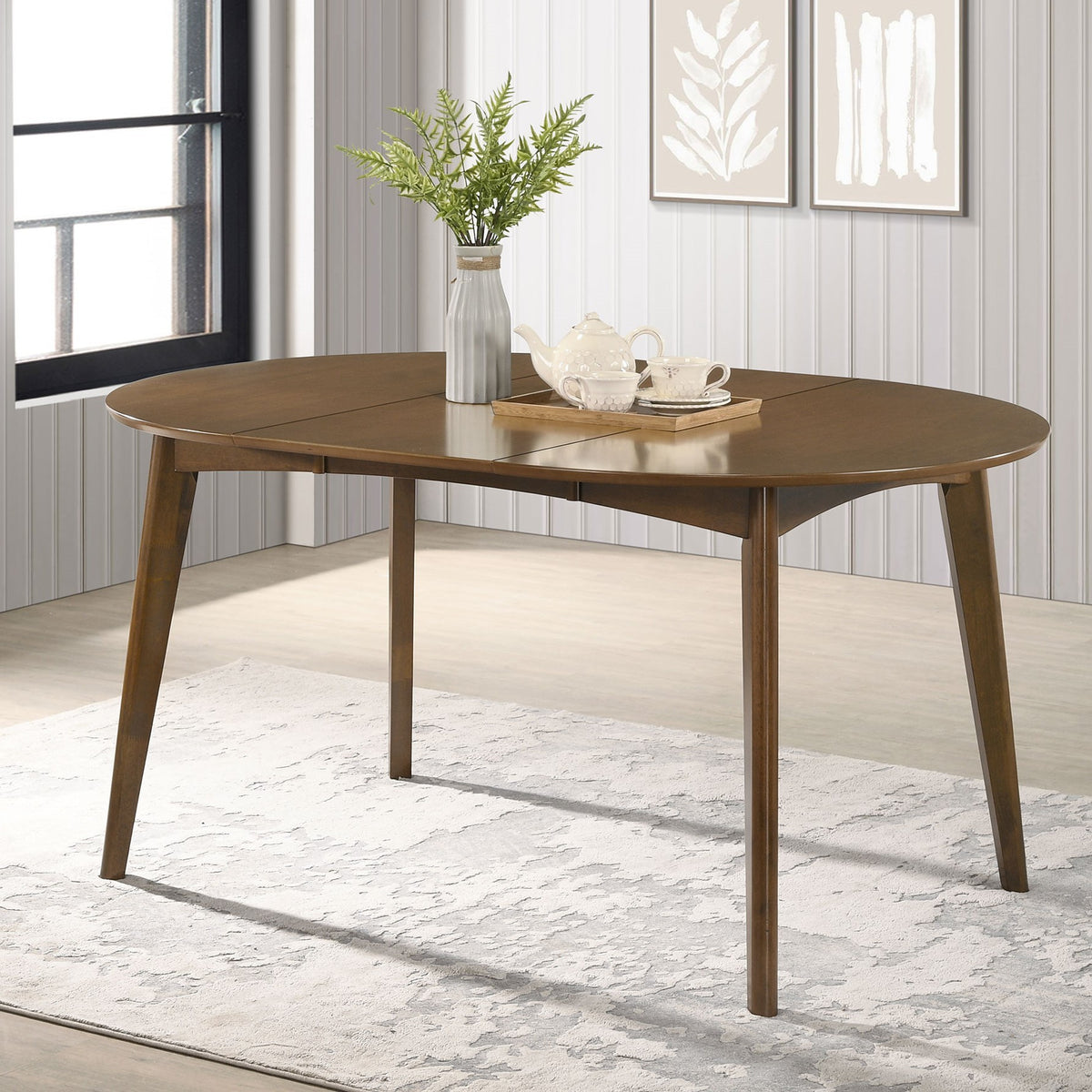 Walnut oval dining table styled with a plant and tea set in a bright room