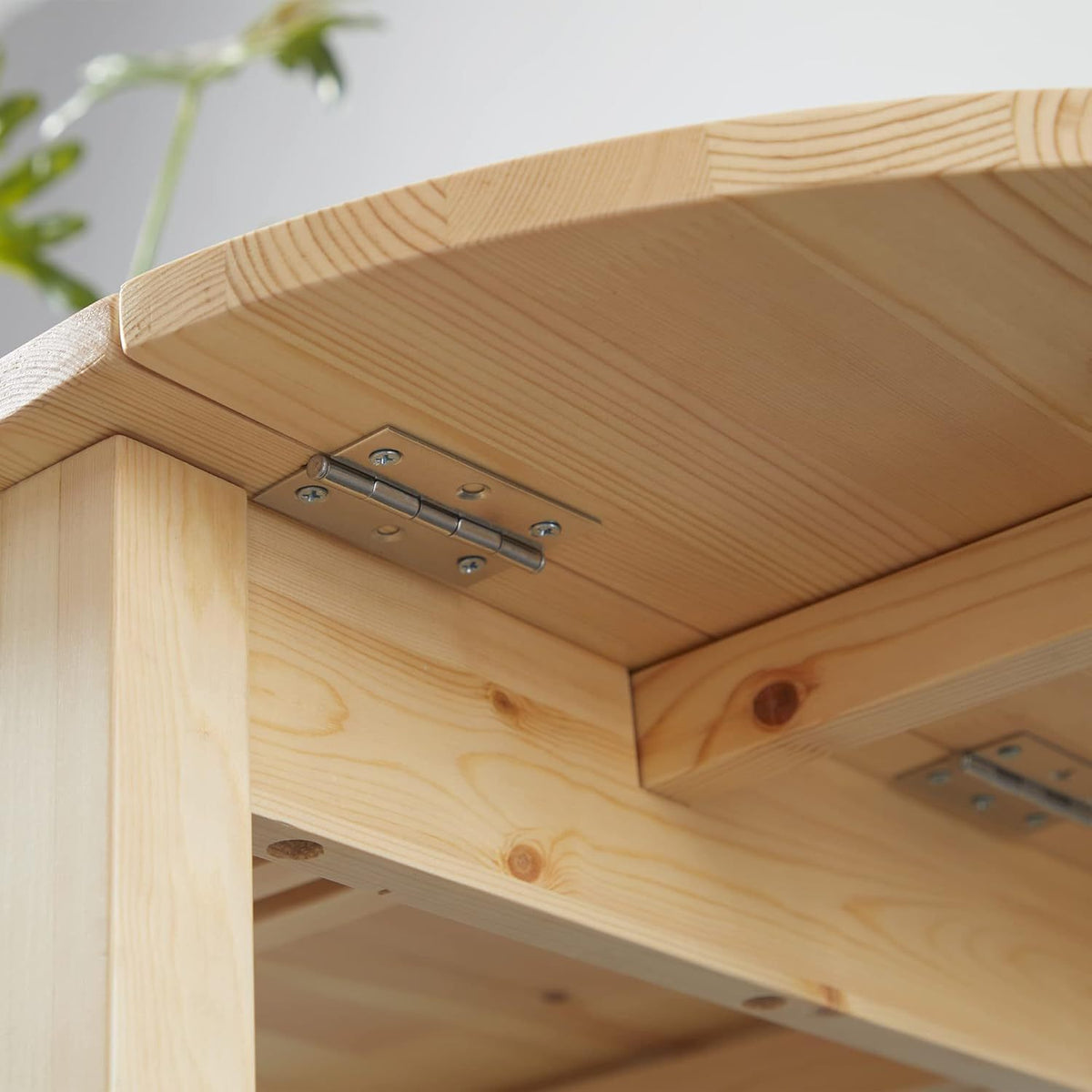 Close-up of the metal drop-leaf hinge joining the leaf to the apron under the pine tabletop