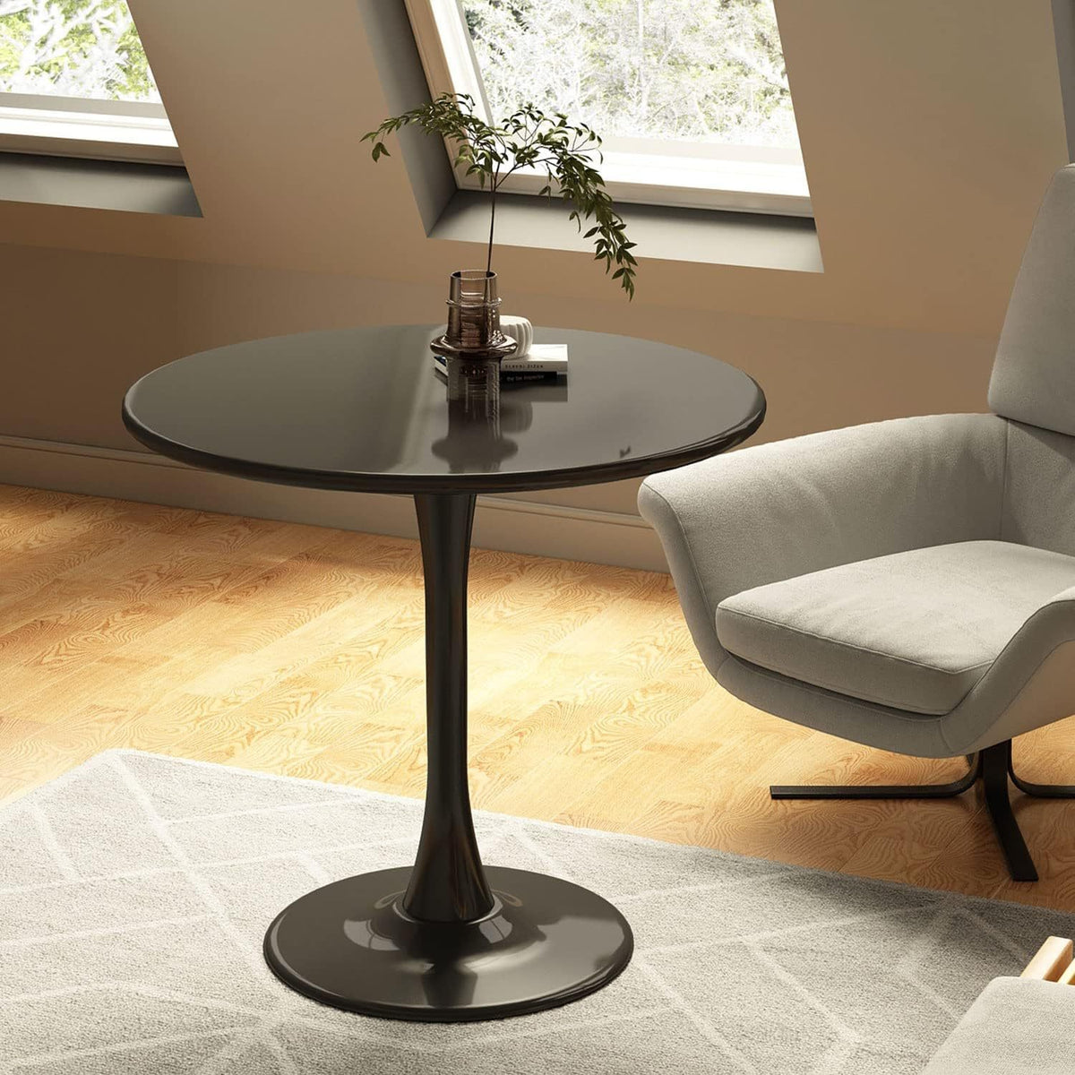 Black round dining table in an attic room with skylights beside a gray armchair