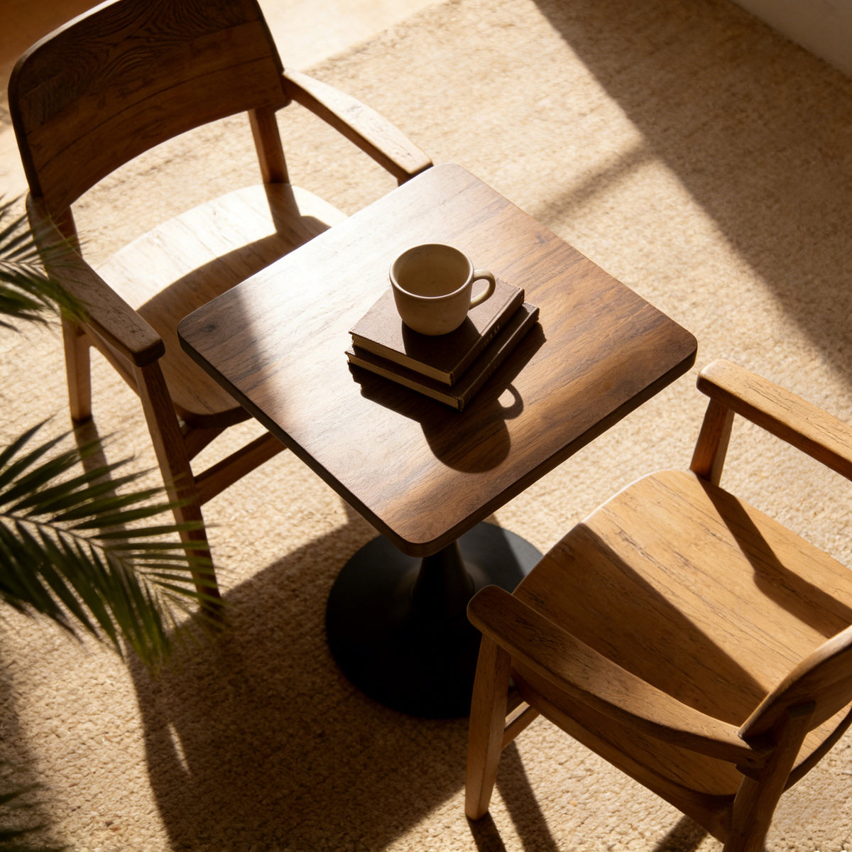 High overhead close-up of the walnut square tulip bistro table with two wood armchairs in warm sunlight
