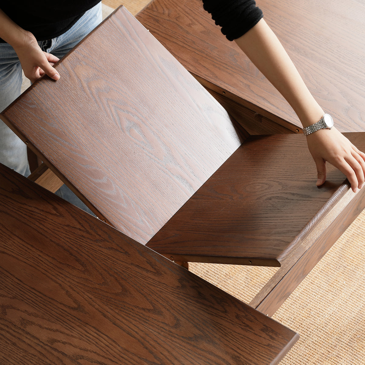 Top-down view of hands opening the table to add the center butterfly leaf