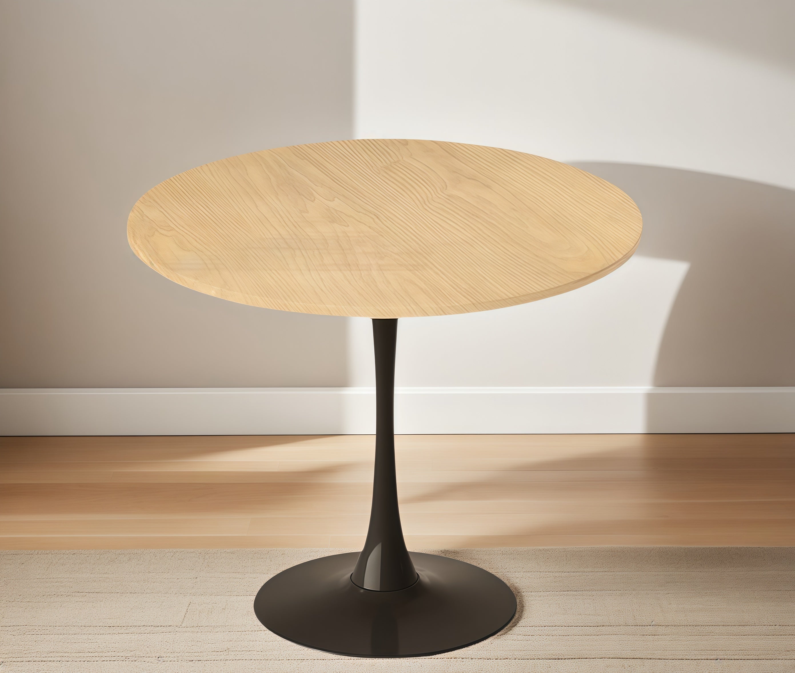 Side angle of the natural wood round bistro table on a rug against a plain wall with no styling