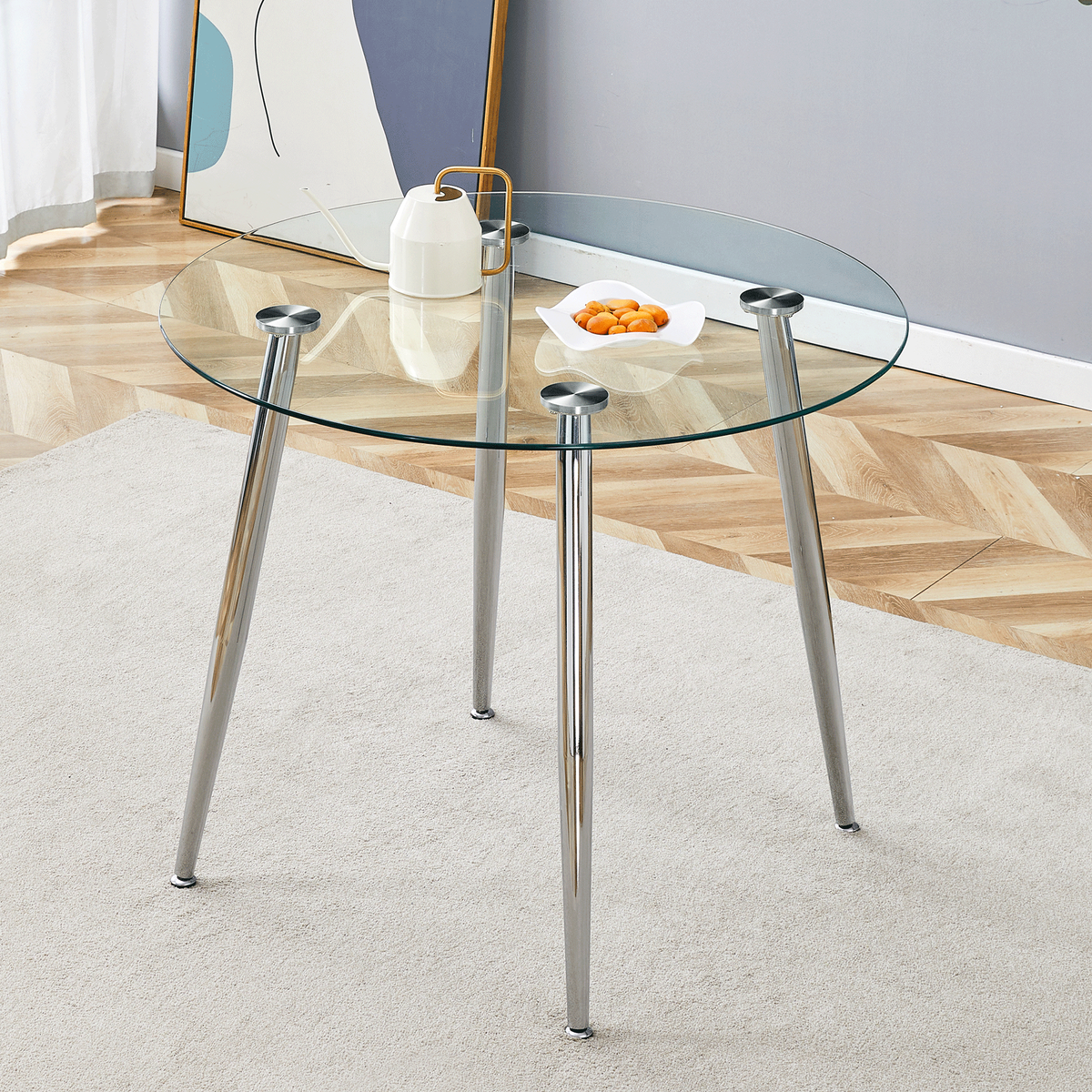 Round glass dining table with tapered silver legs in a styled living room, three-quarter view