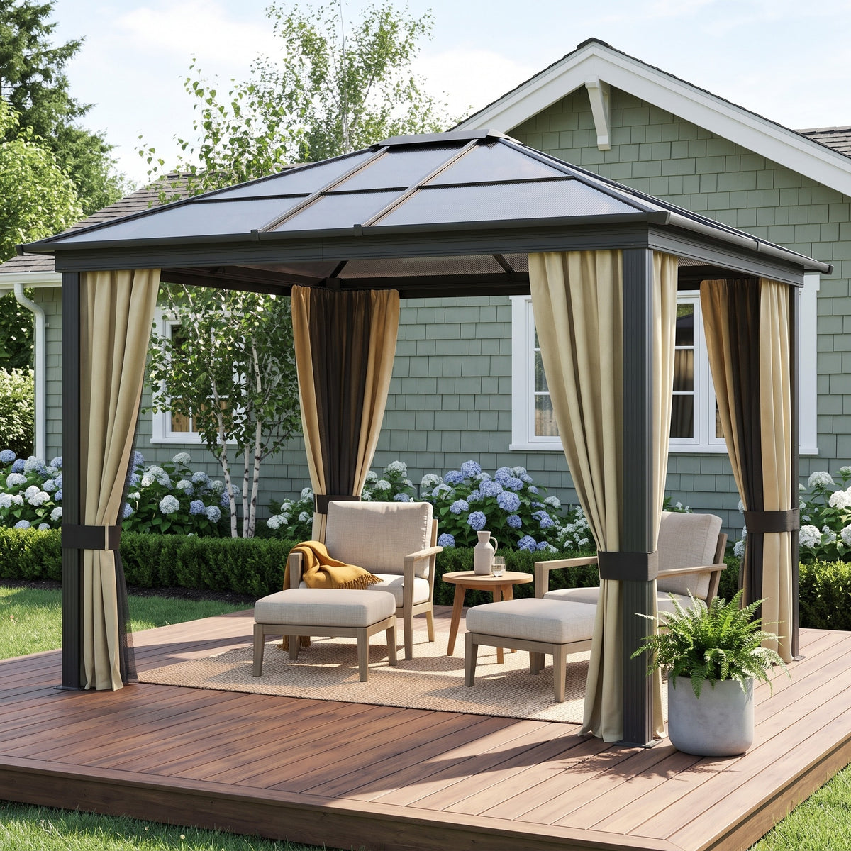 Gray aluminum hardtop gazebo with beige curtains over lounge chairs on a wood deck beside a sage green house