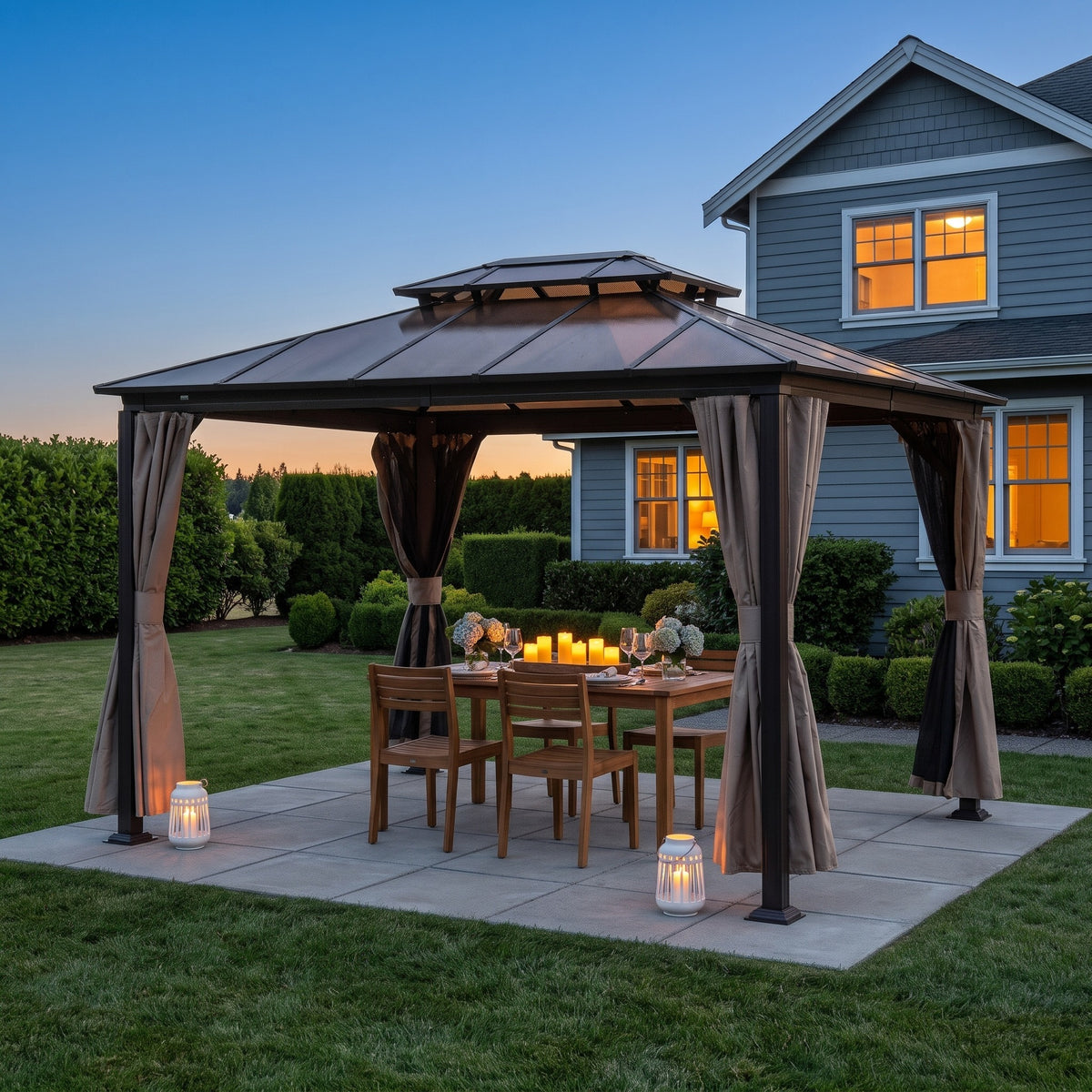 Brown aluminum 10x12 double roof gazebo with tied back tan curtains over a teak dining table on a patio at dusk