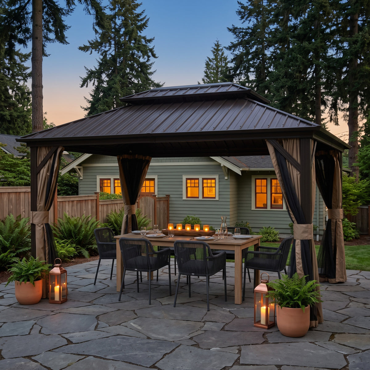 Brown aluminum 10x12 double roof gazebo with tan curtains over a dining table on a stone patio at dusk