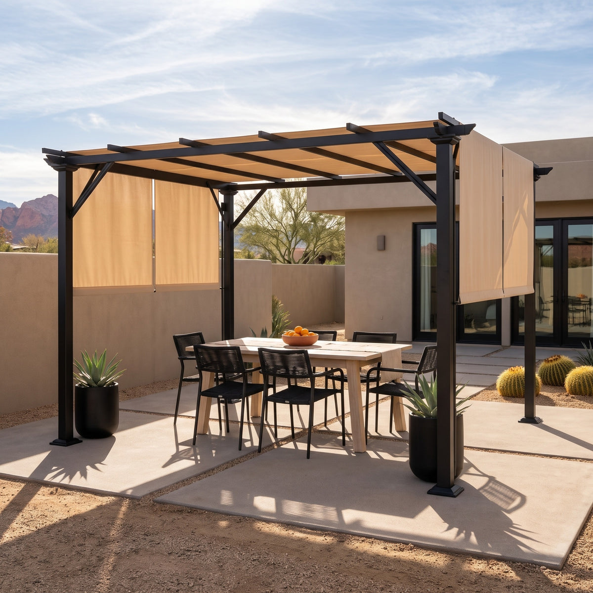 Black steel pergola with beige retractable canopy over an outdoor dining table on a desert concrete patio