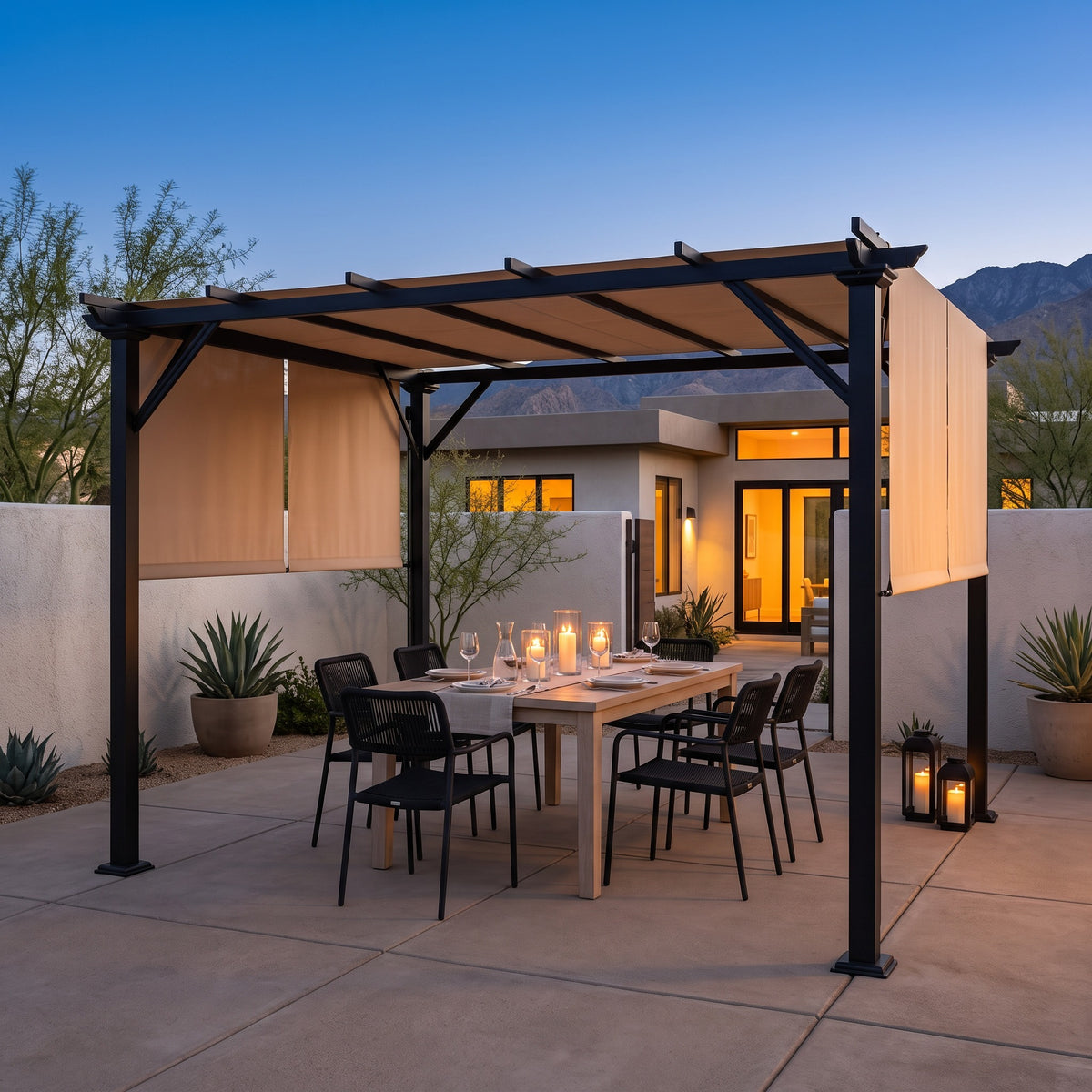 Black steel pergola with beige retractable canopy over a dining table on a concrete patio at dusk