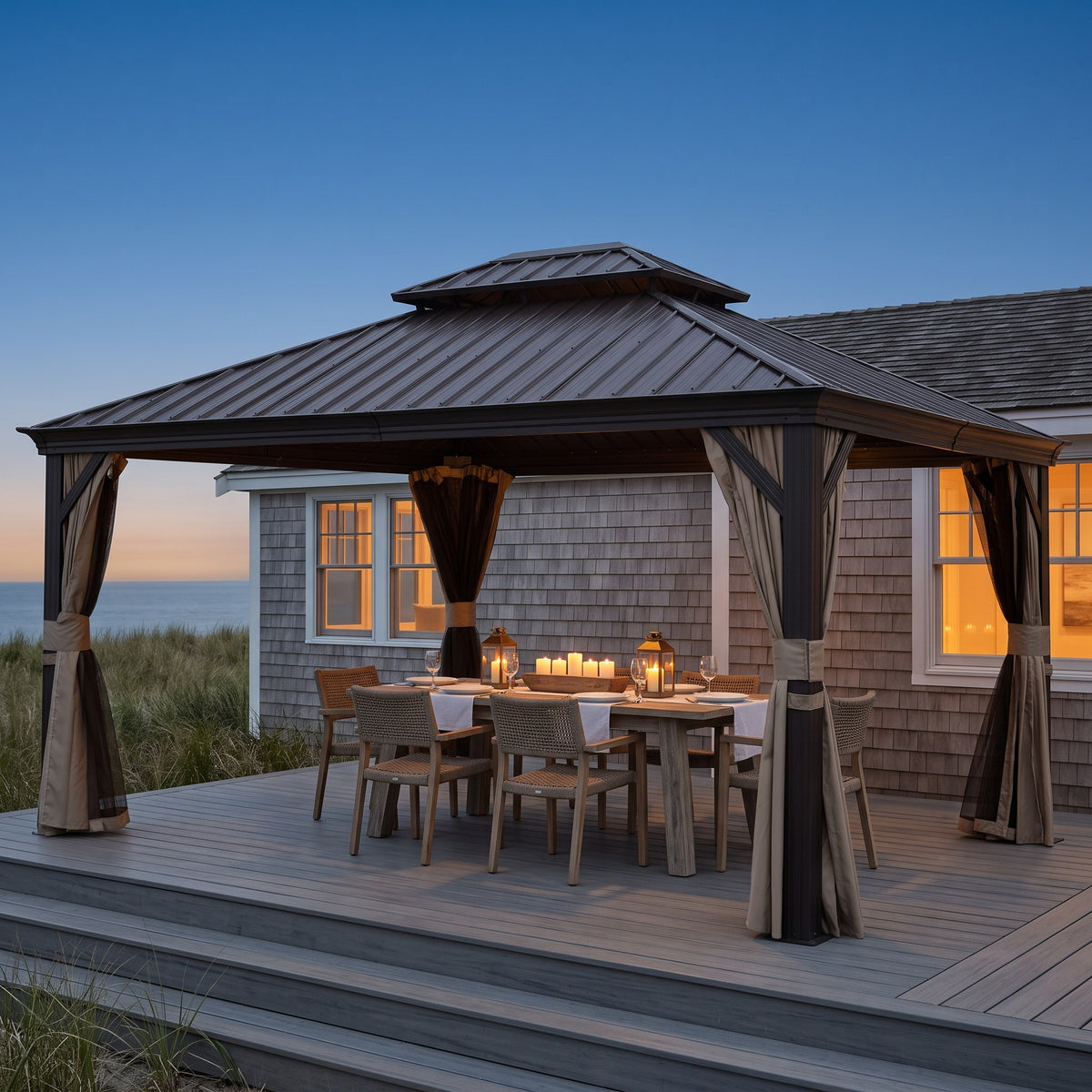 Brown 10x14 double roof hardtop gazebo with tied back curtains over a candlelit dining table on a beach deck at dusk