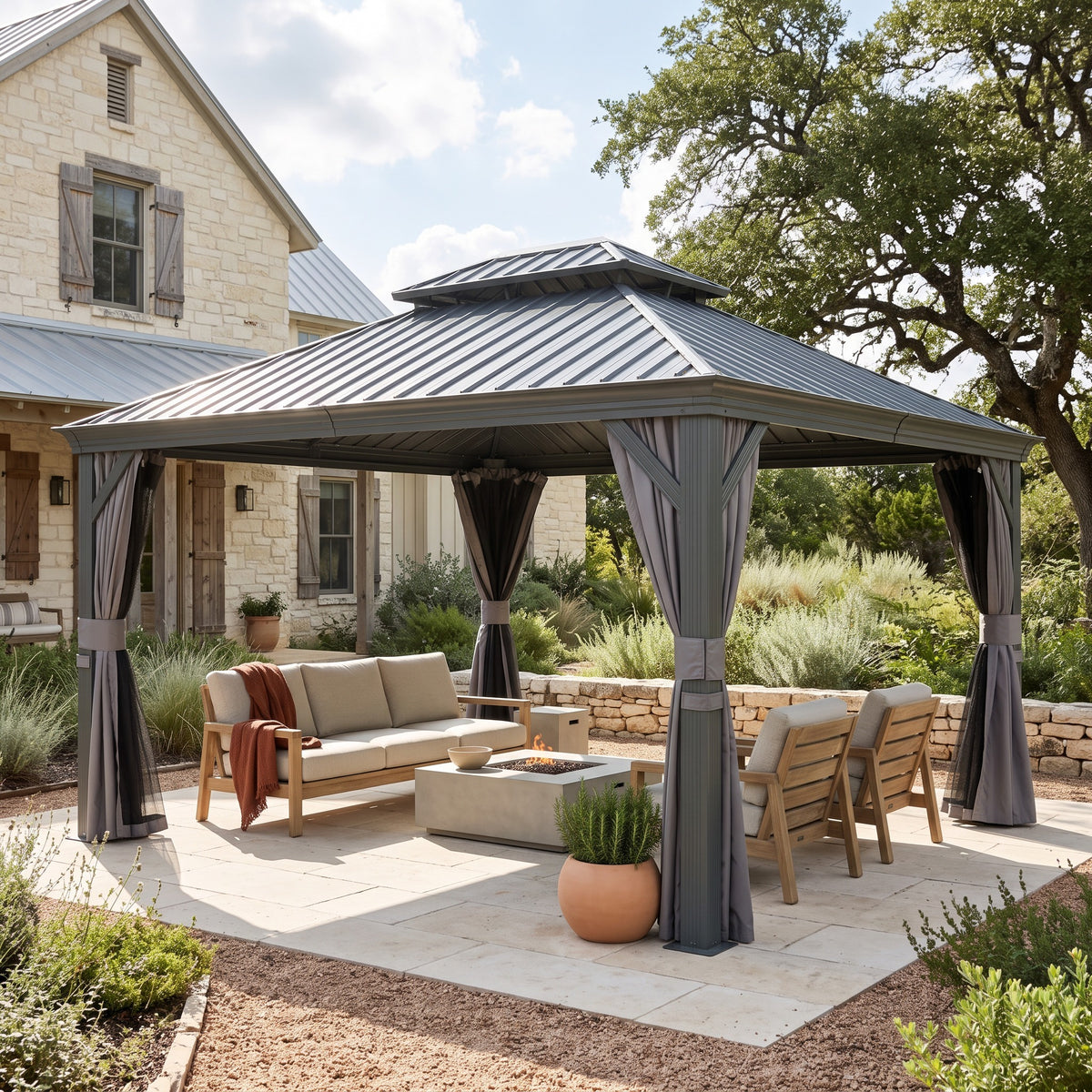 Gray aluminum 10x14 hardtop gazebo with double roof and tied curtains over a lounge set on a stone patio