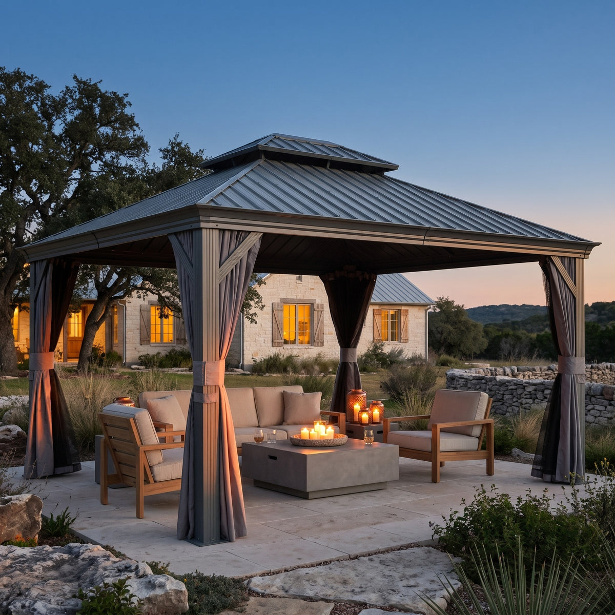 Gray aluminum 10x14 double roof hardtop gazebo with tied back curtains over a candlelit patio seating area at dusk