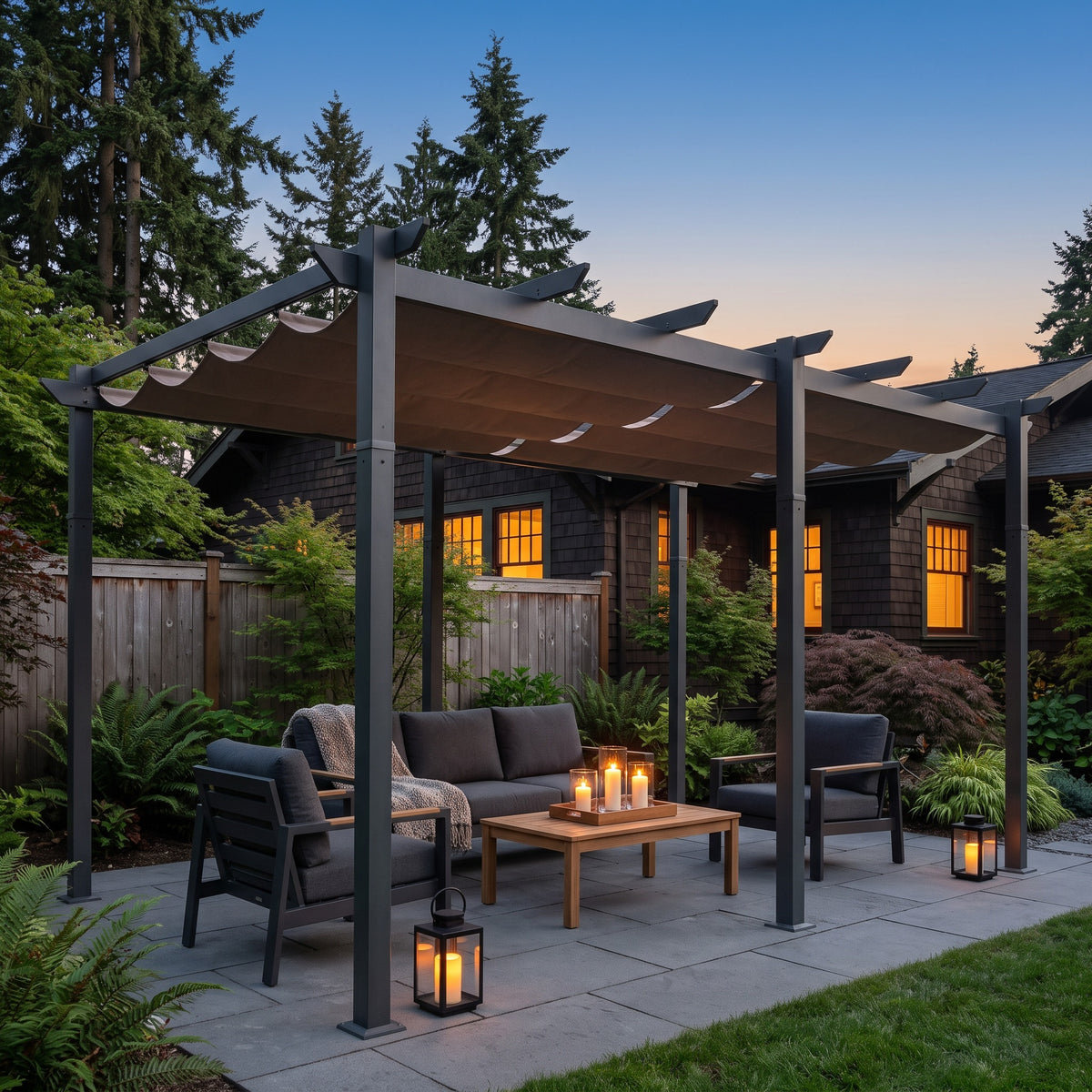 Dark gray aluminum pergola with taupe retractable canopy over a patio sofa set at dusk with candle lanterns