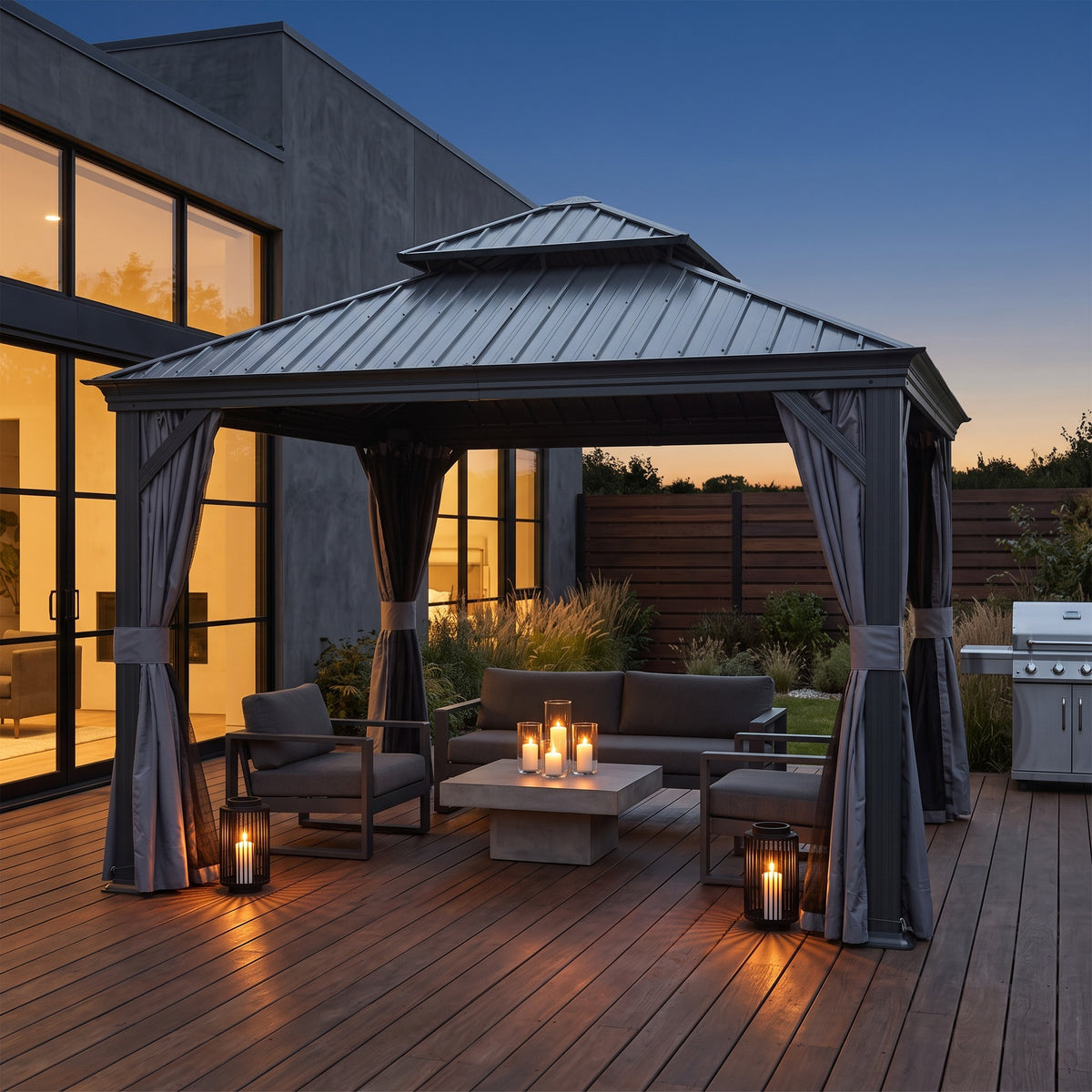 Gray 12x12 hardtop gazebo with tied back curtains over a sofa and candles on a wood deck at dusk