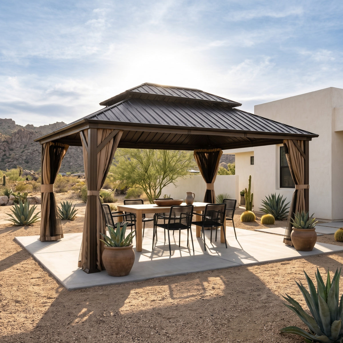 Brown aluminum 12x14 hardtop gazebo with beige curtains over a dining table on a desert concrete patio