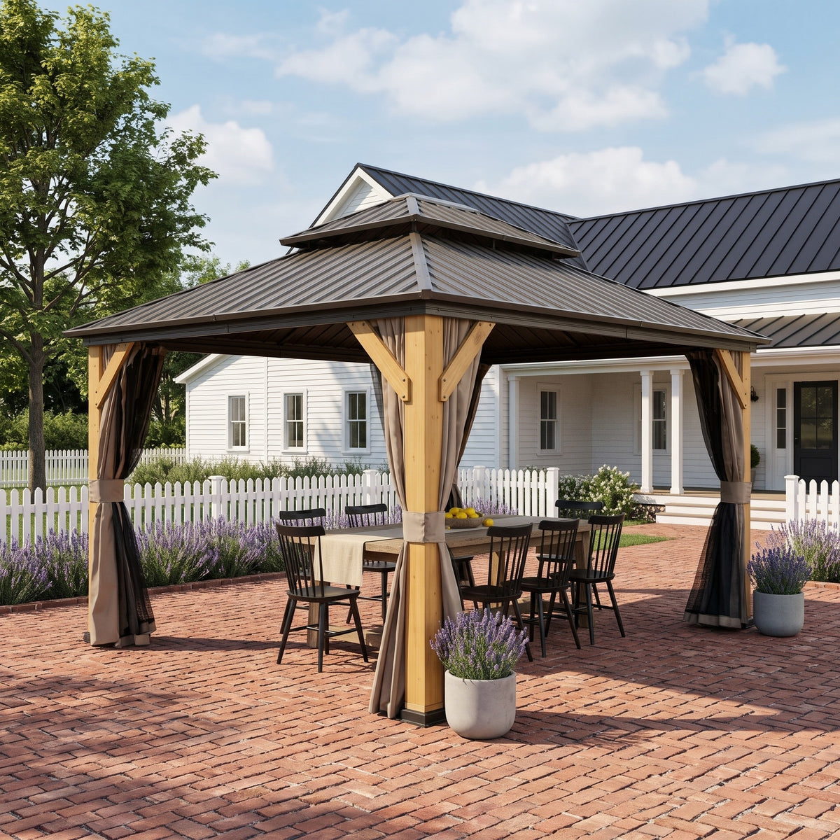 Brown wood double roof hardtop gazebo with tan curtains over a dining table on a brick patio by a white farmhouse