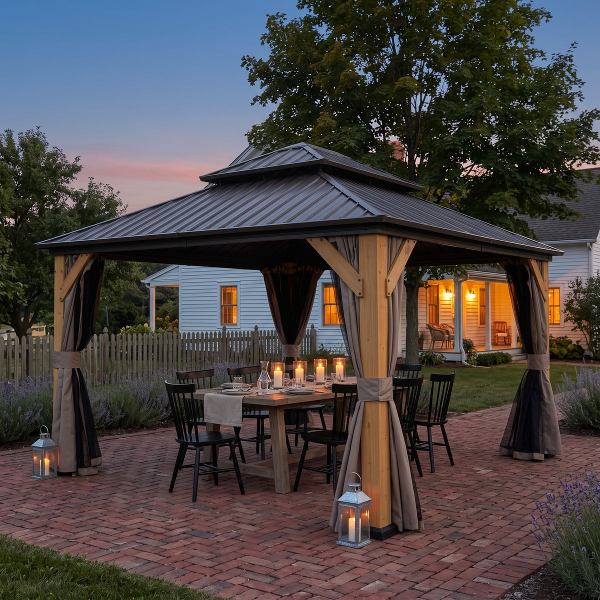 Brown wood double roof hardtop gazebo with tied back curtains over a candlelit dining table on a brick patio at dusk