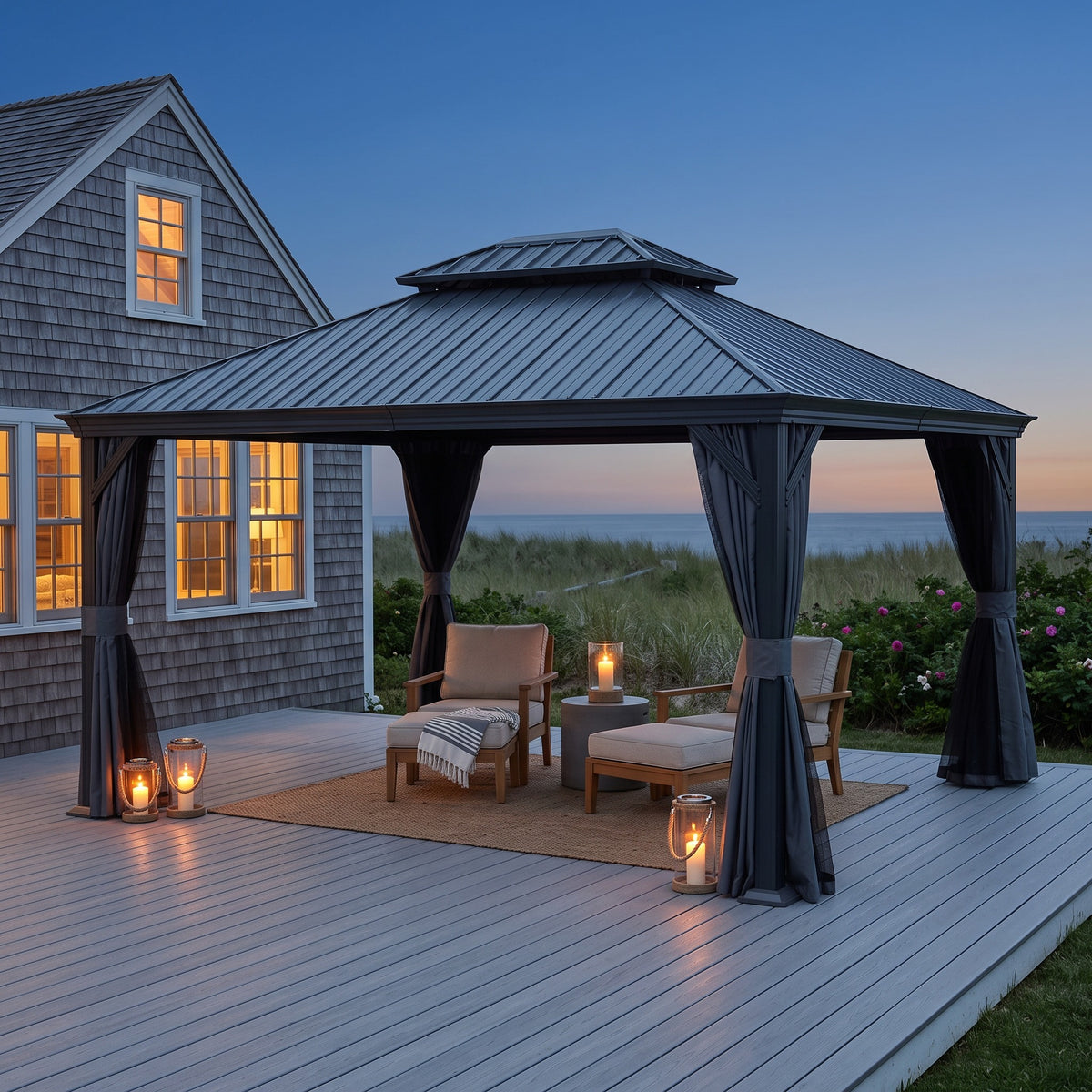 Dark gray 12x14 hardtop gazebo with tied back curtains over lounge chairs on a deck at dusk with candle lanterns