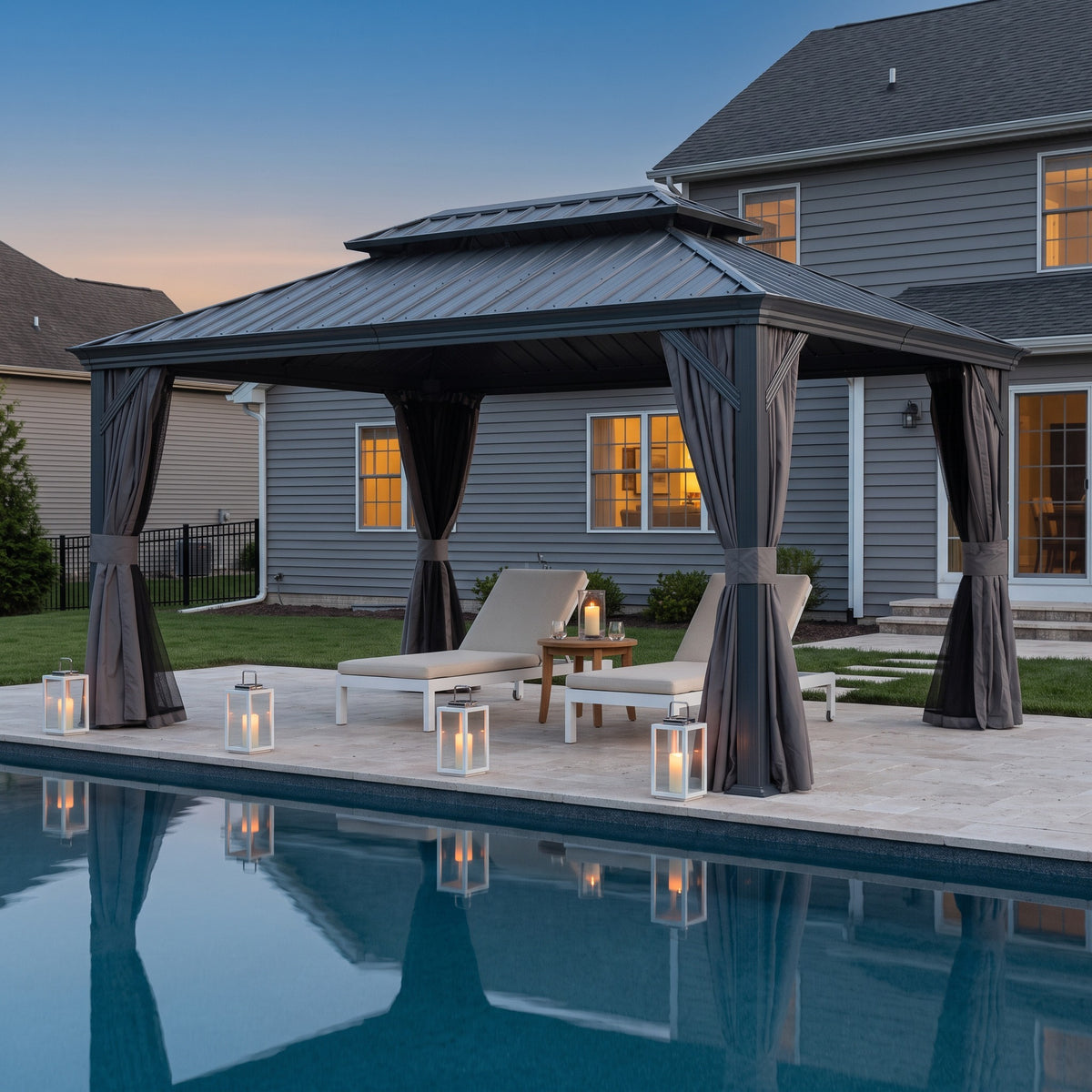 Gray 12x14 hardtop gazebo with tied back curtains over two lounge chairs beside a pool at dusk with candle lanterns