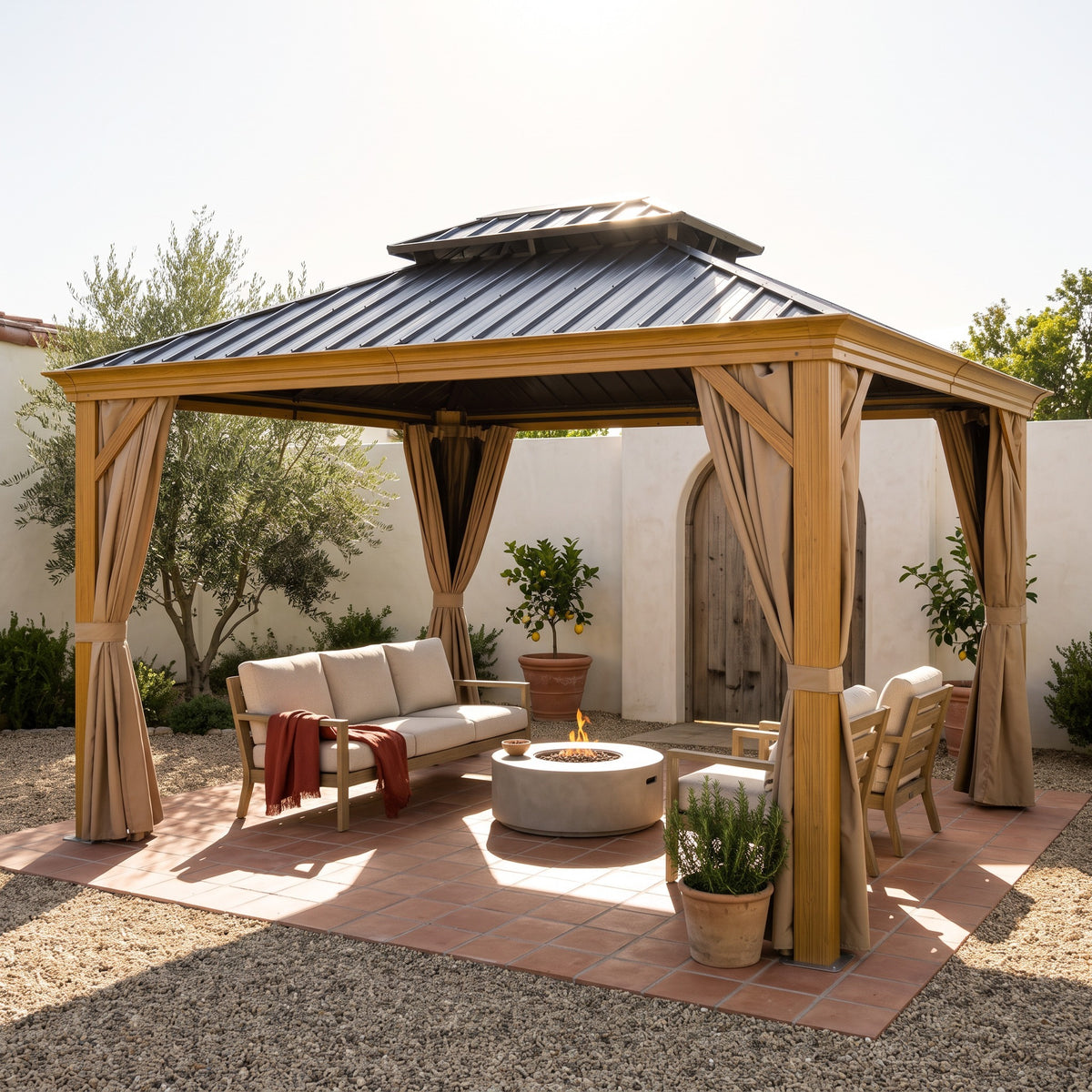 Yellow brown aluminum hardtop gazebo with tan curtains over a sofa and fire table on a terracotta patio
