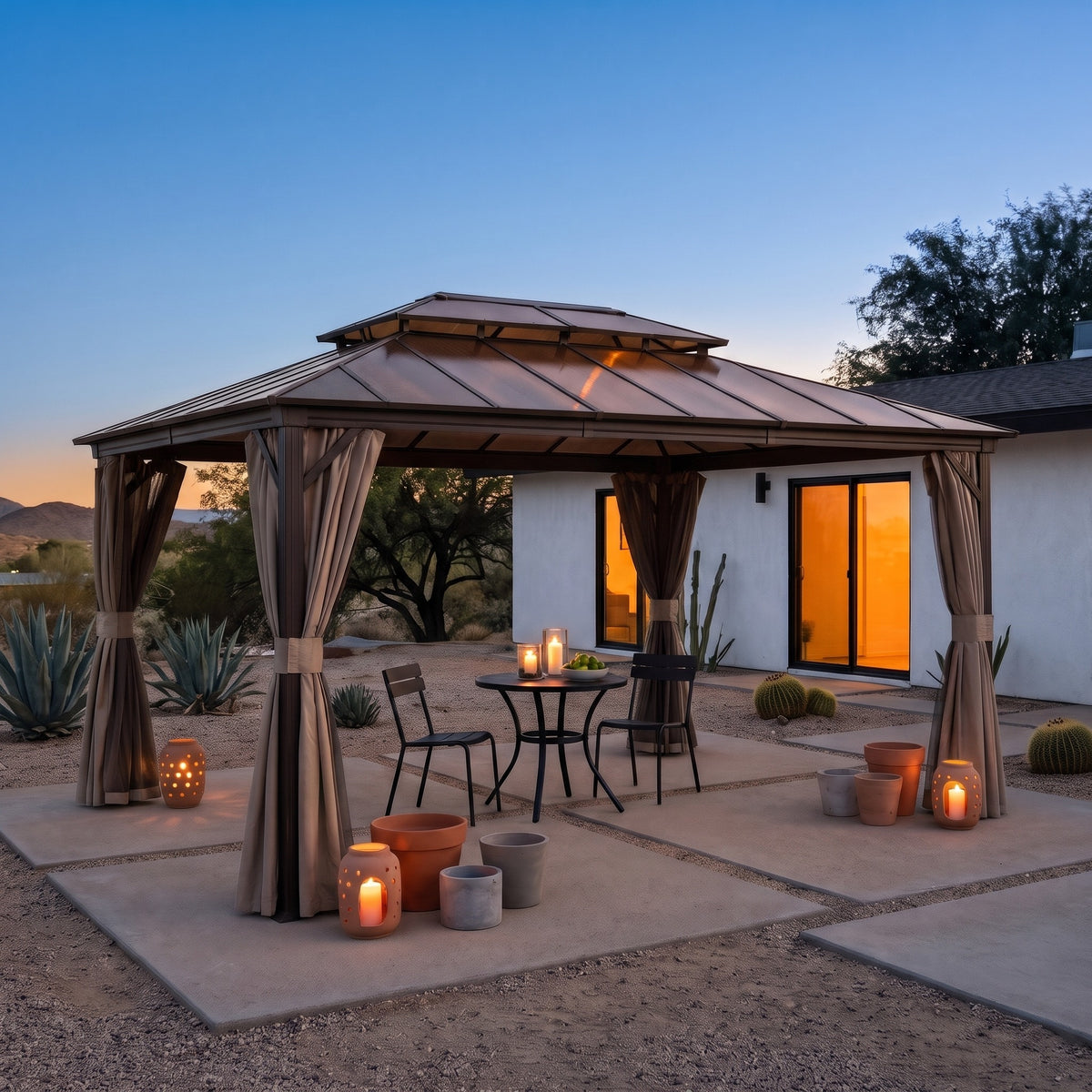 Brown aluminum 12x16 double roof gazebo with tied back curtains over a bistro table on a desert patio at dusk